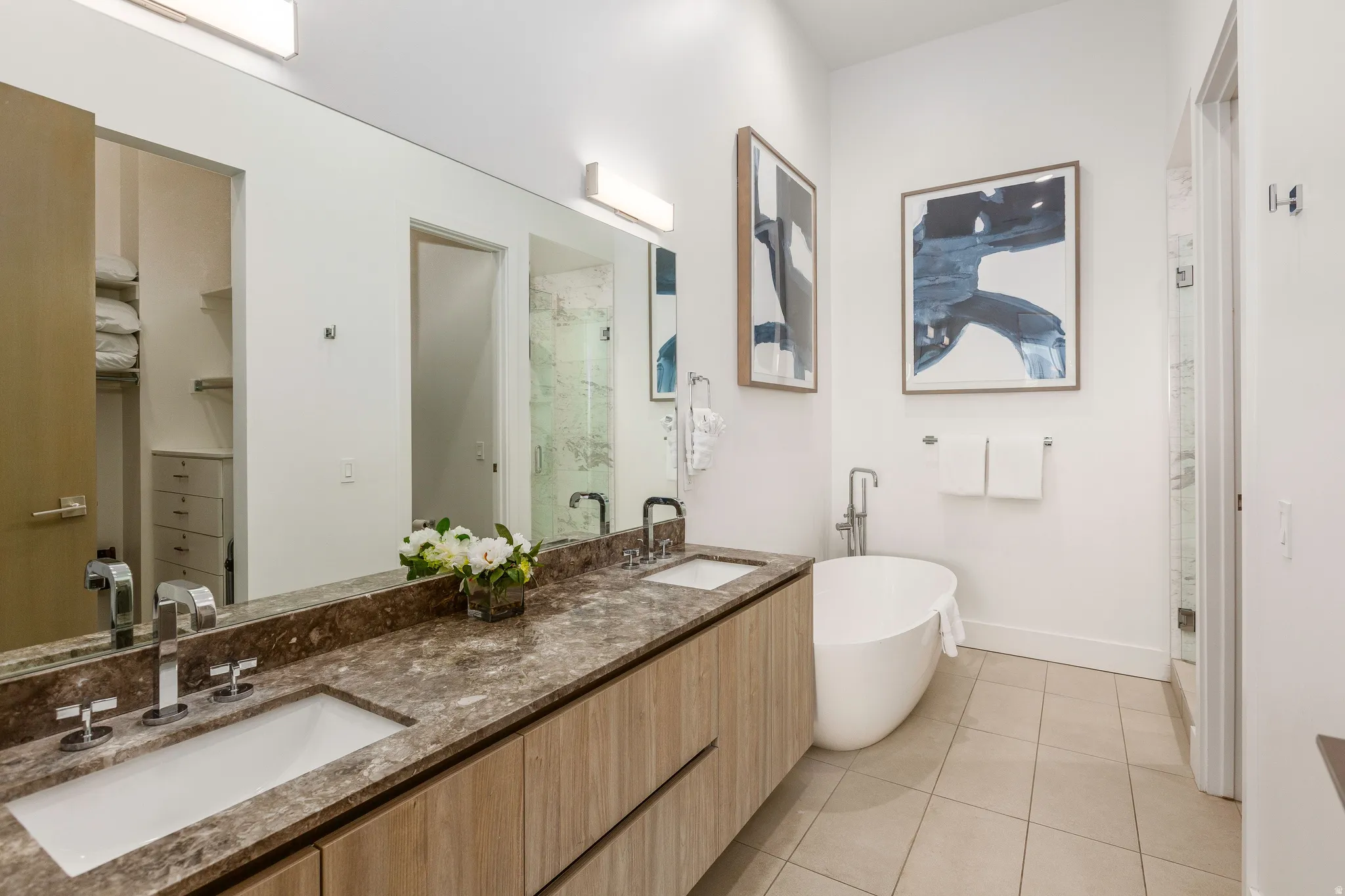 Bathroom featuring a marble finish shower, double vanity, a soaking tub, light tile patterned flooring, and a spacious closet