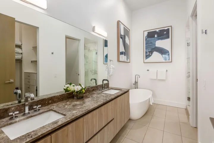 Bathroom featuring a marble finish shower, double vanity, a soaking tub, light tile patterned flooring, and a spacious closet