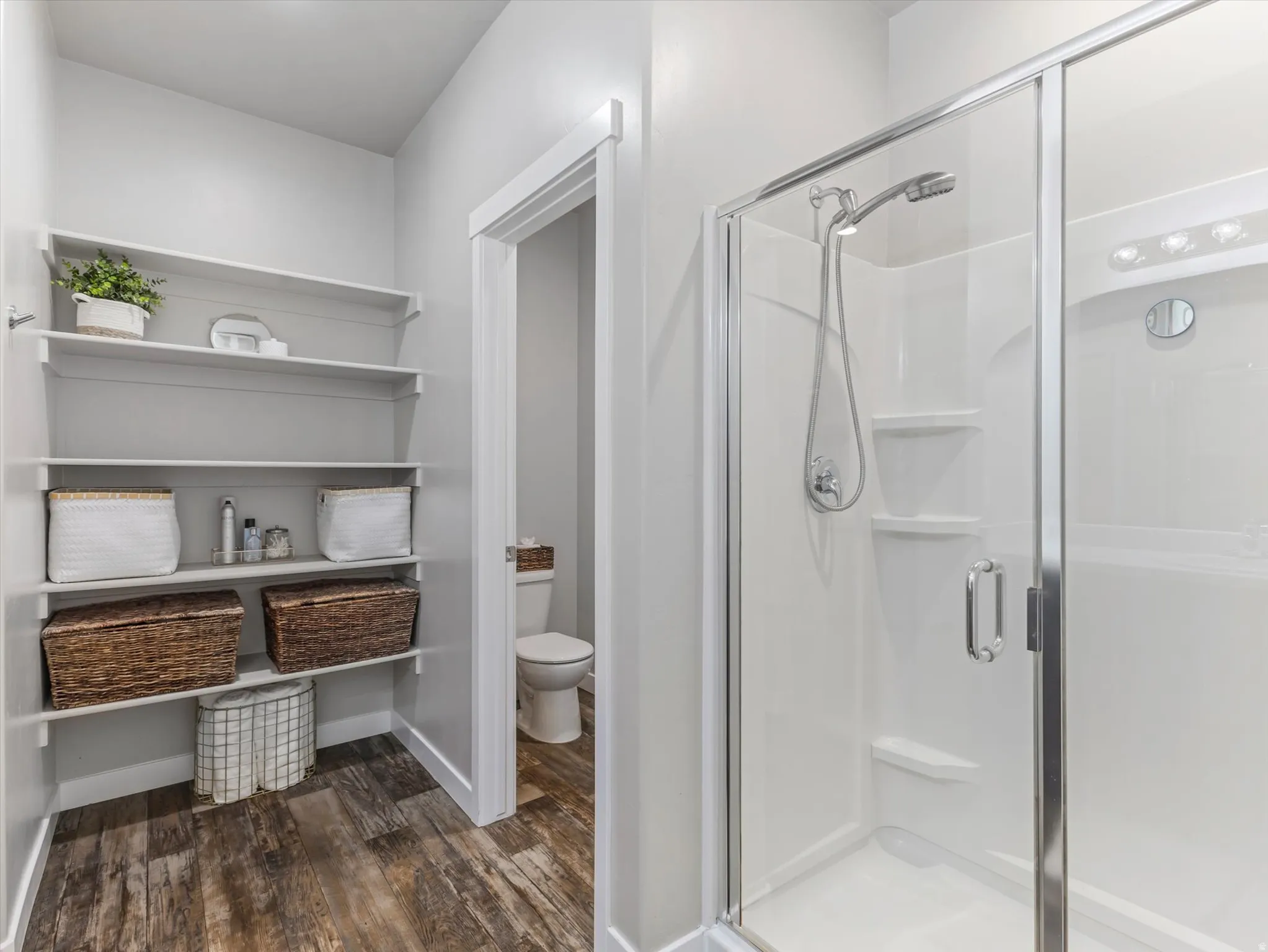 Full bath with a stall shower and dark wood-style floors