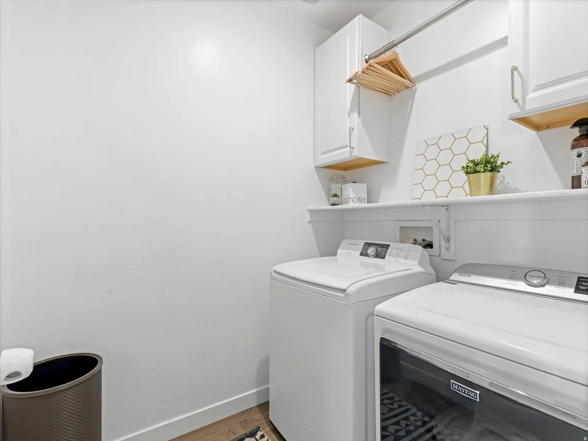 Laundry room featuring separate washer and dryer, cabinet space, and light wood-style flooring