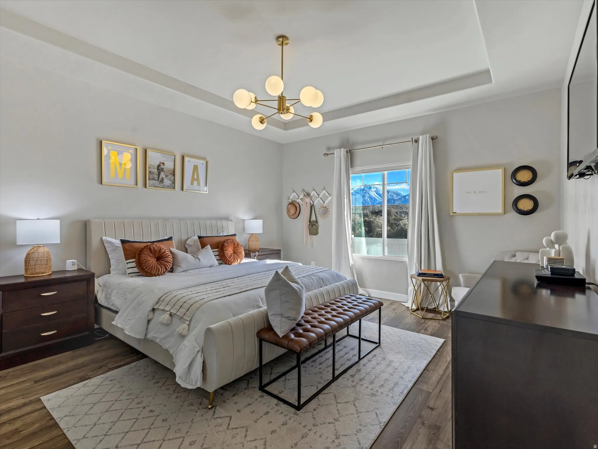 Bedroom with hanging lights, a tray ceiling, and dark wood-type flooring