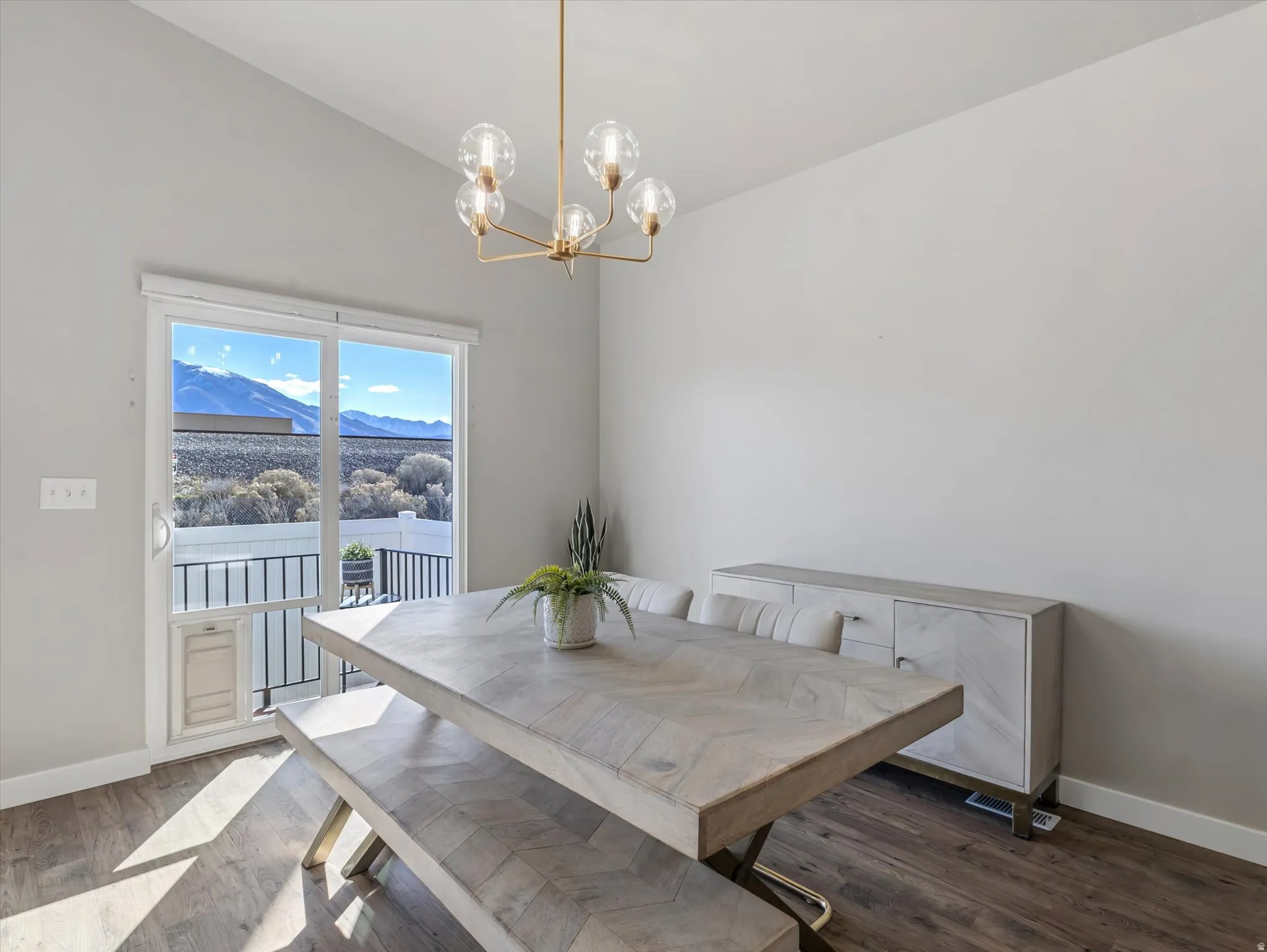 Dining room featuring a mountain view, hanging lights, wood finished floors, and vaulted ceiling