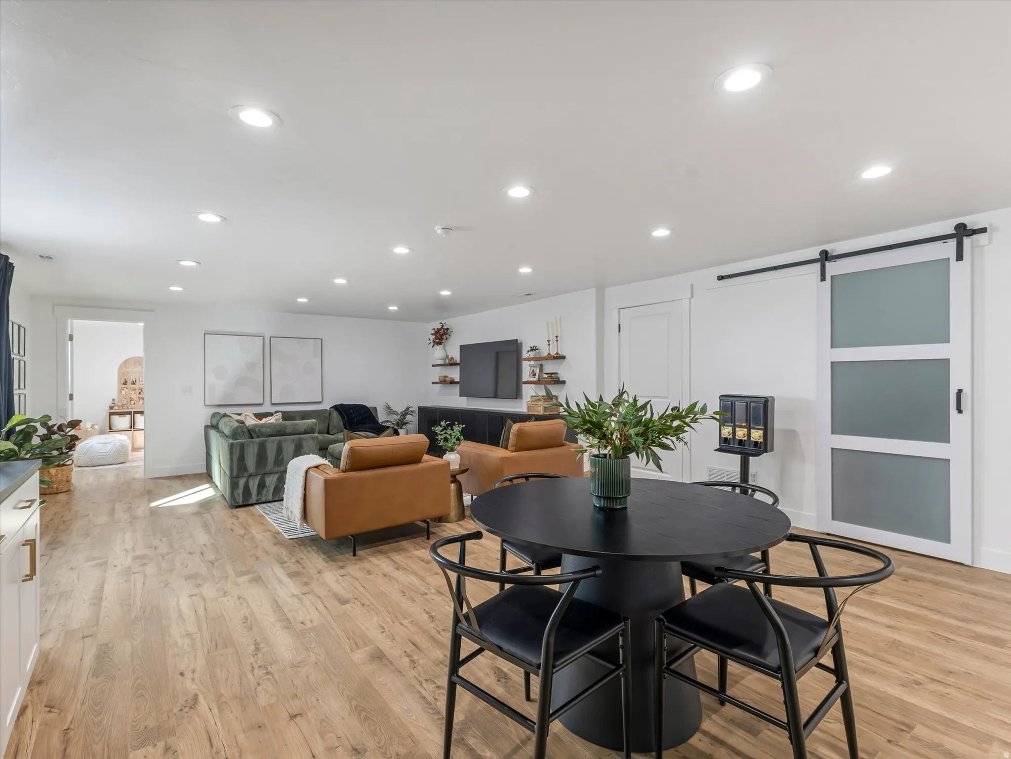 Dining space with a barn door, light wood-type flooring, and recessed lighting