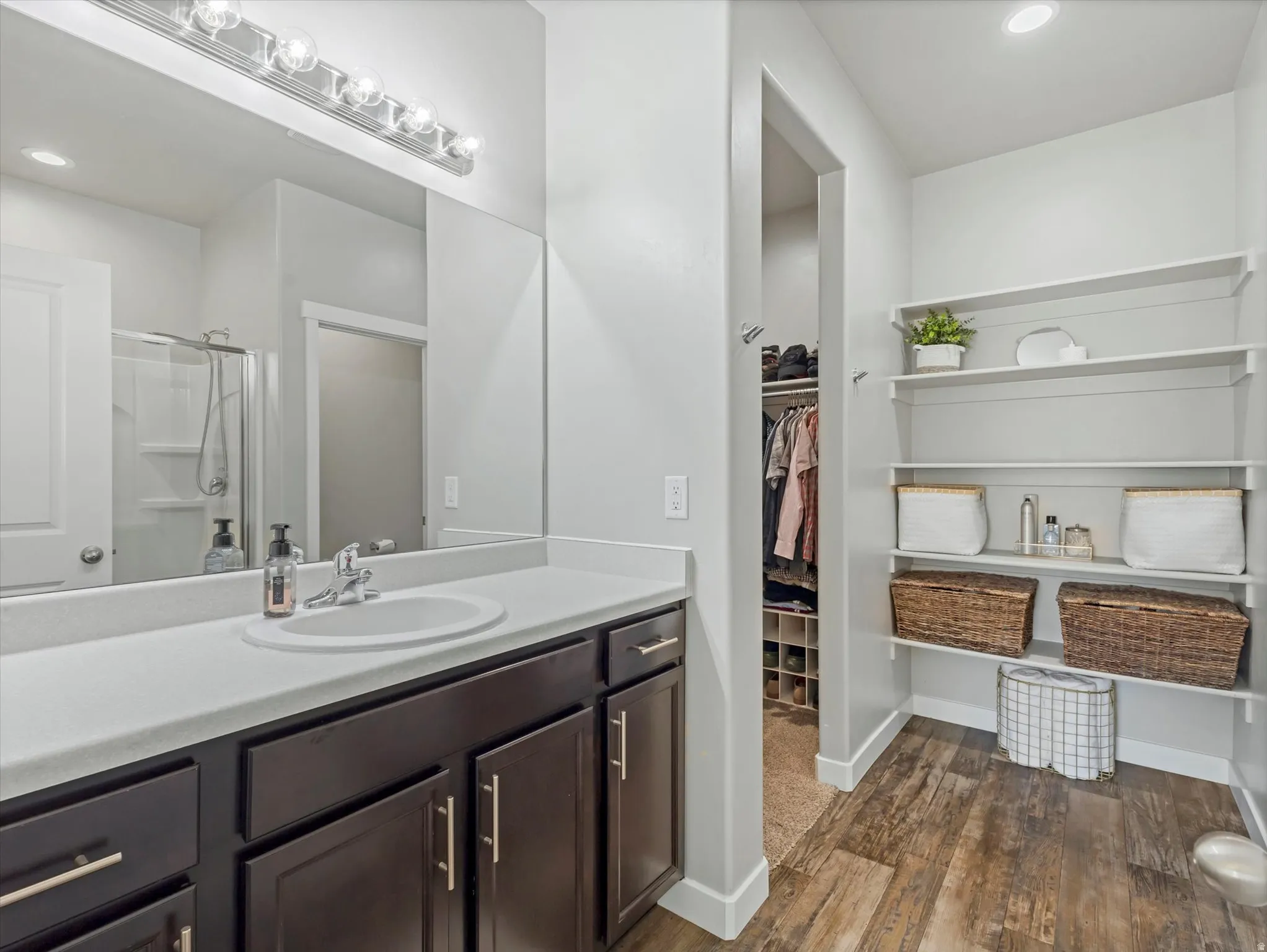 Bathroom featuring recessed lighting, vanity, dark wood-style floors, a shower stall, and a walk in closet