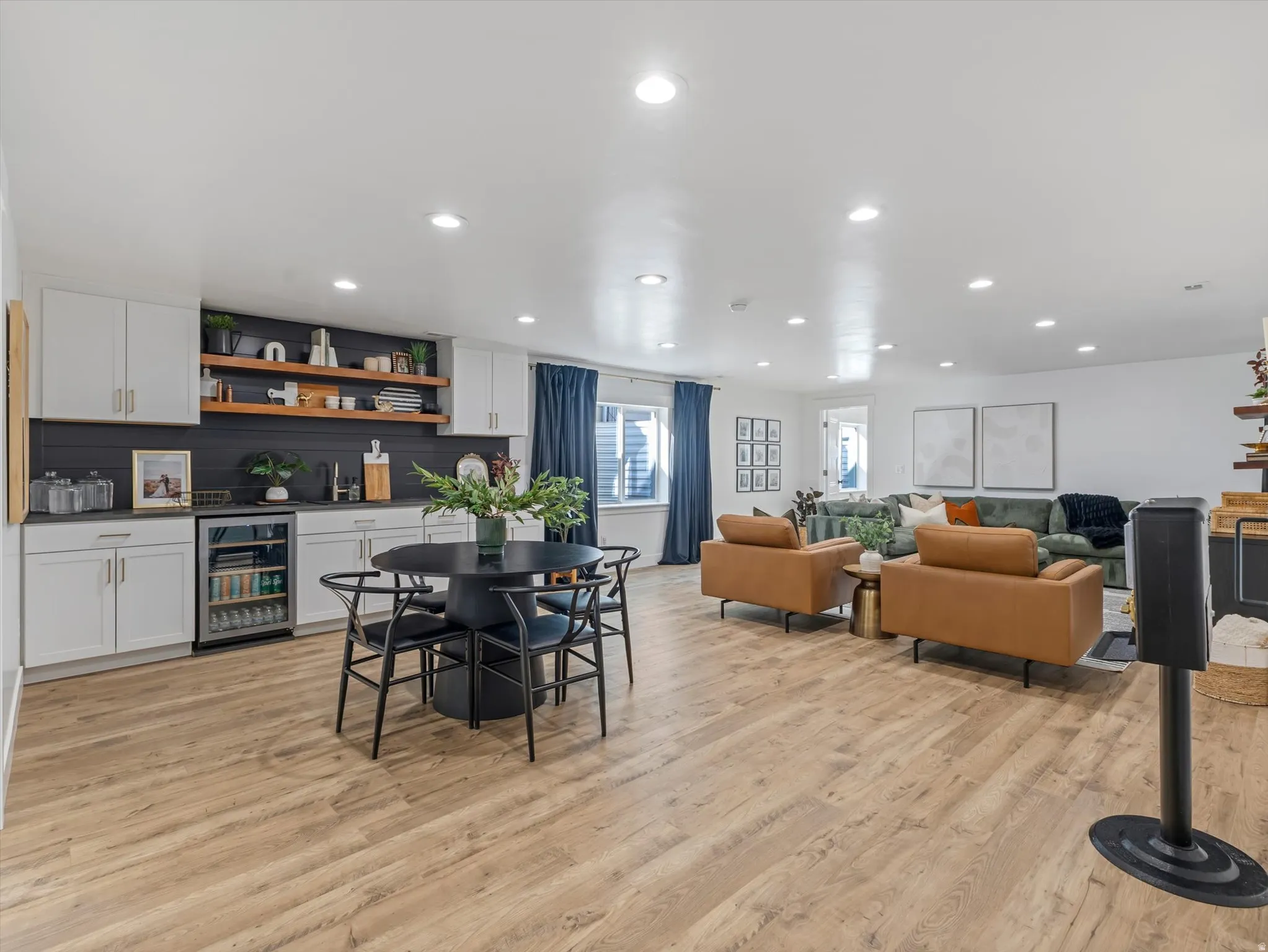 Dining area featuring beverage cooler, light wood finished floors, recessed lighting, and a dry bar