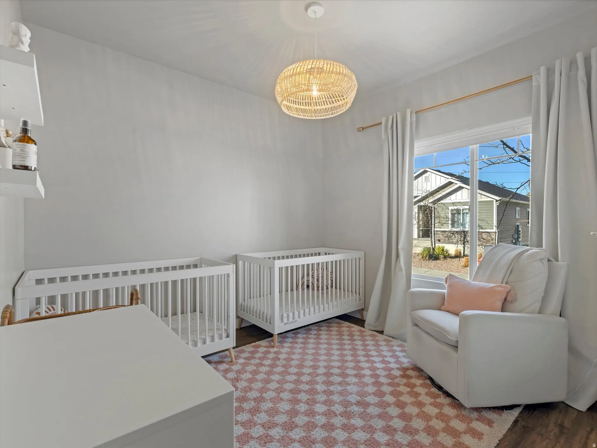 Bedroom featuring a nursery area, light wood finished floors, and a chandelier