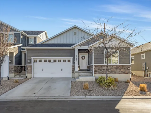 Craftsman-style house with stone siding, board and batten siding, an attached garage, and concrete driveway