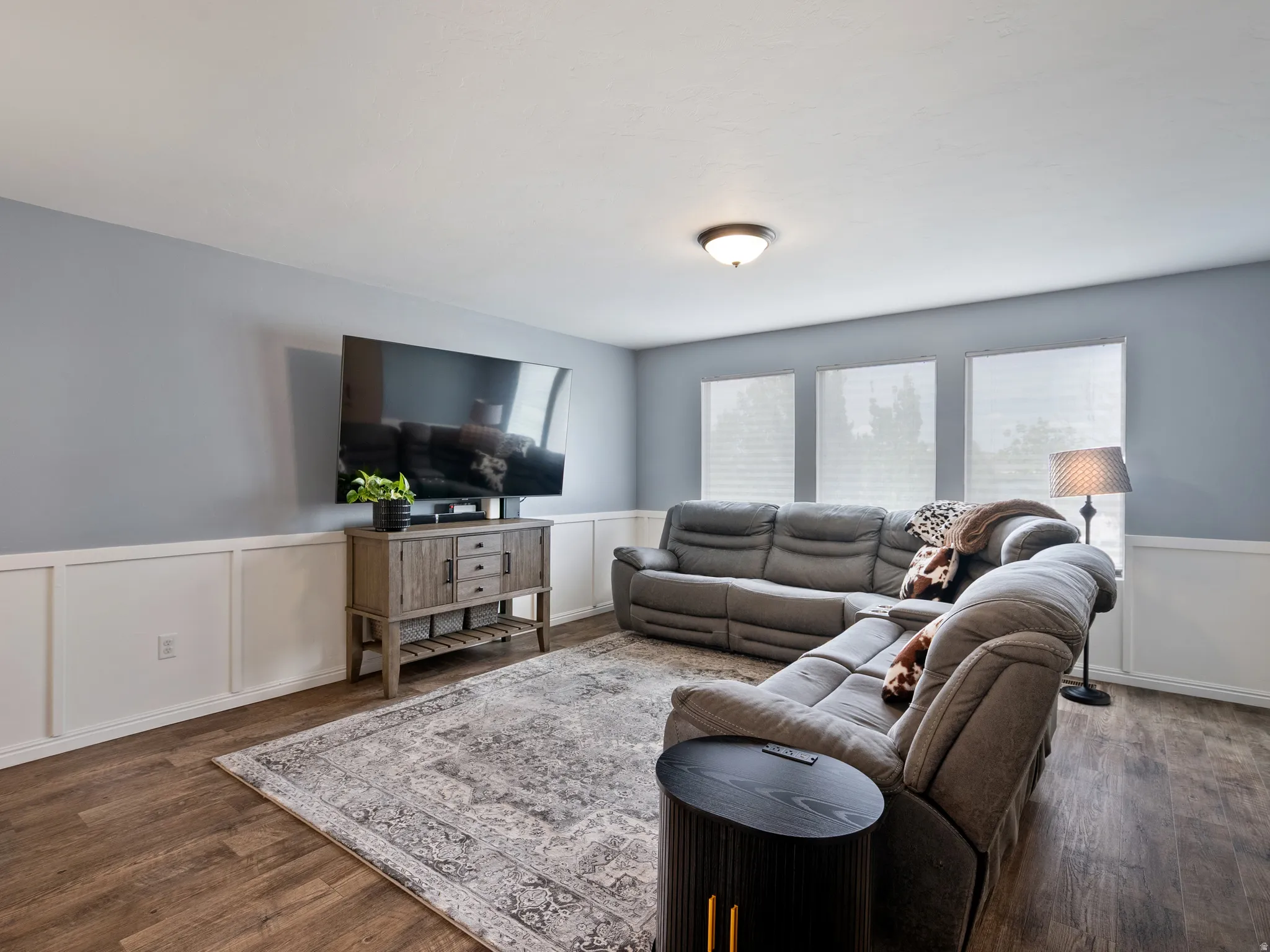 Living area featuring wainscoting, a decorative wall, and dark wood finished floors