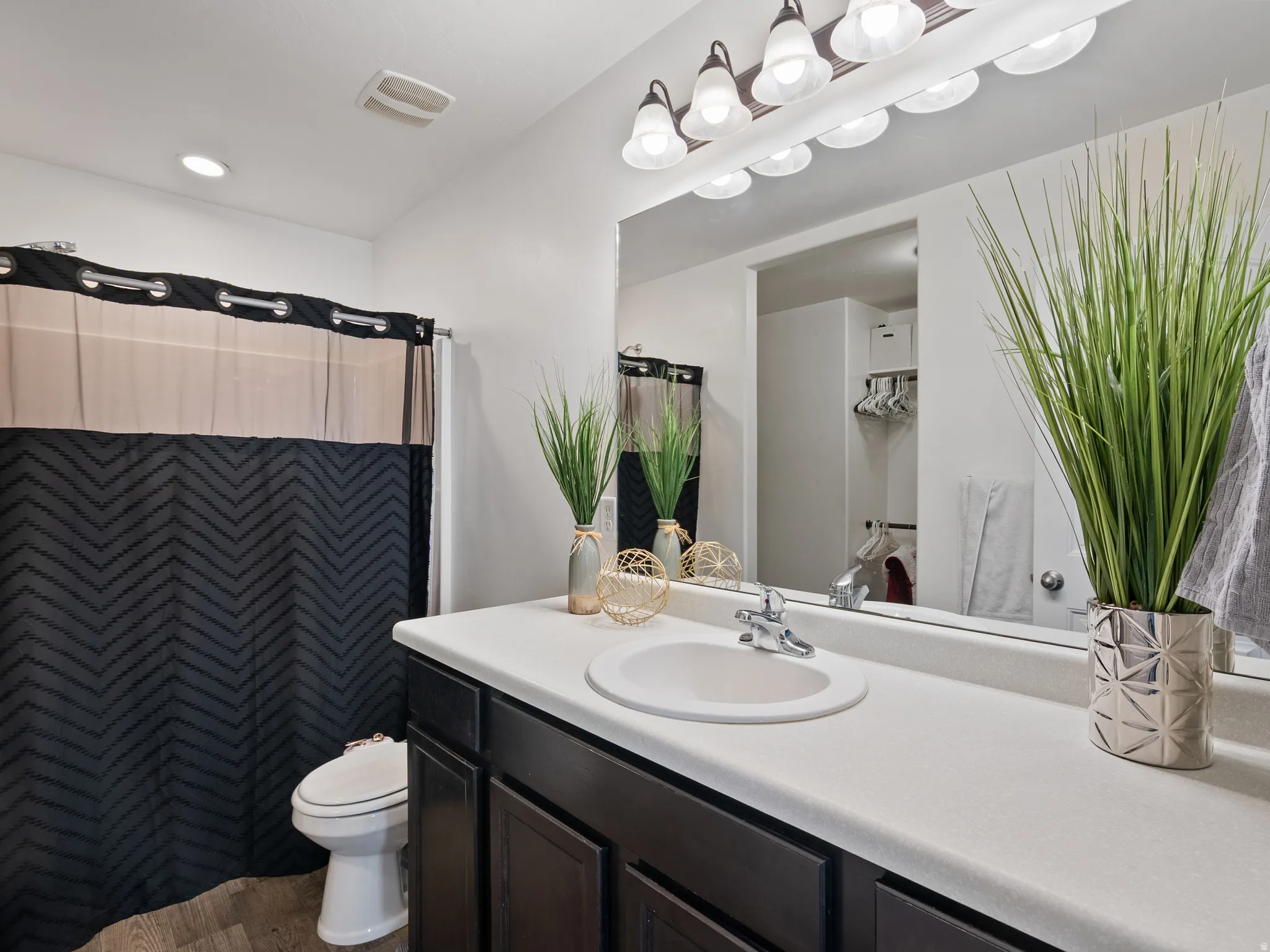 Full bath with vanity, a shower with shower curtain, and light wood-style floors