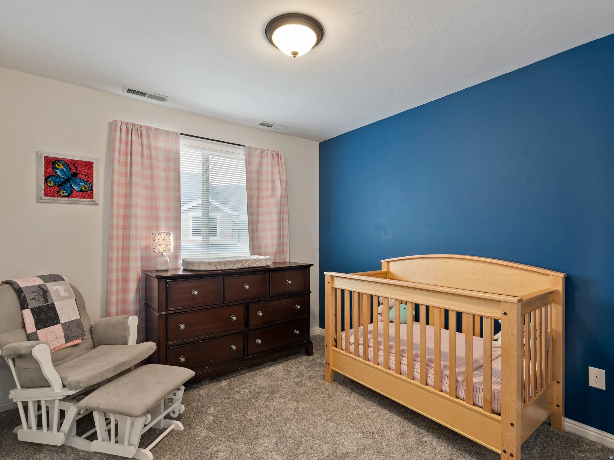 Bedroom with light colored carpet and a crib