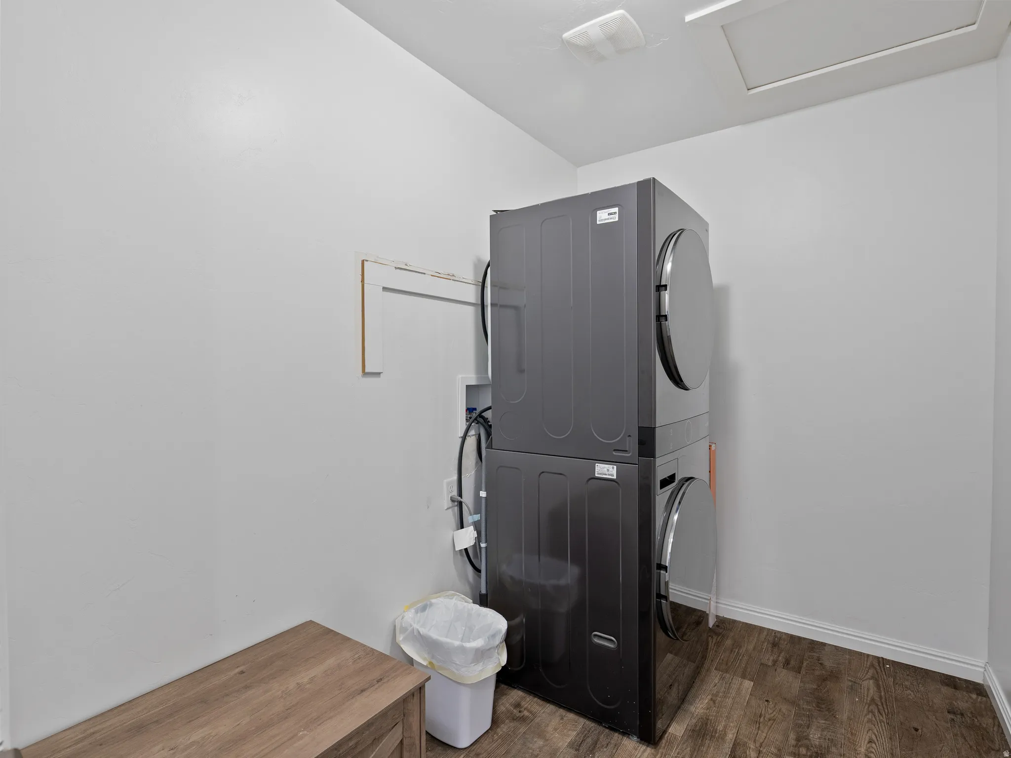 Laundry area with stacked washing machine and dryer and dark wood-style floors