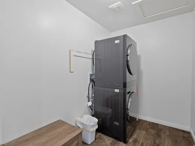 Laundry area with stacked washing machine and dryer and dark wood-style floors