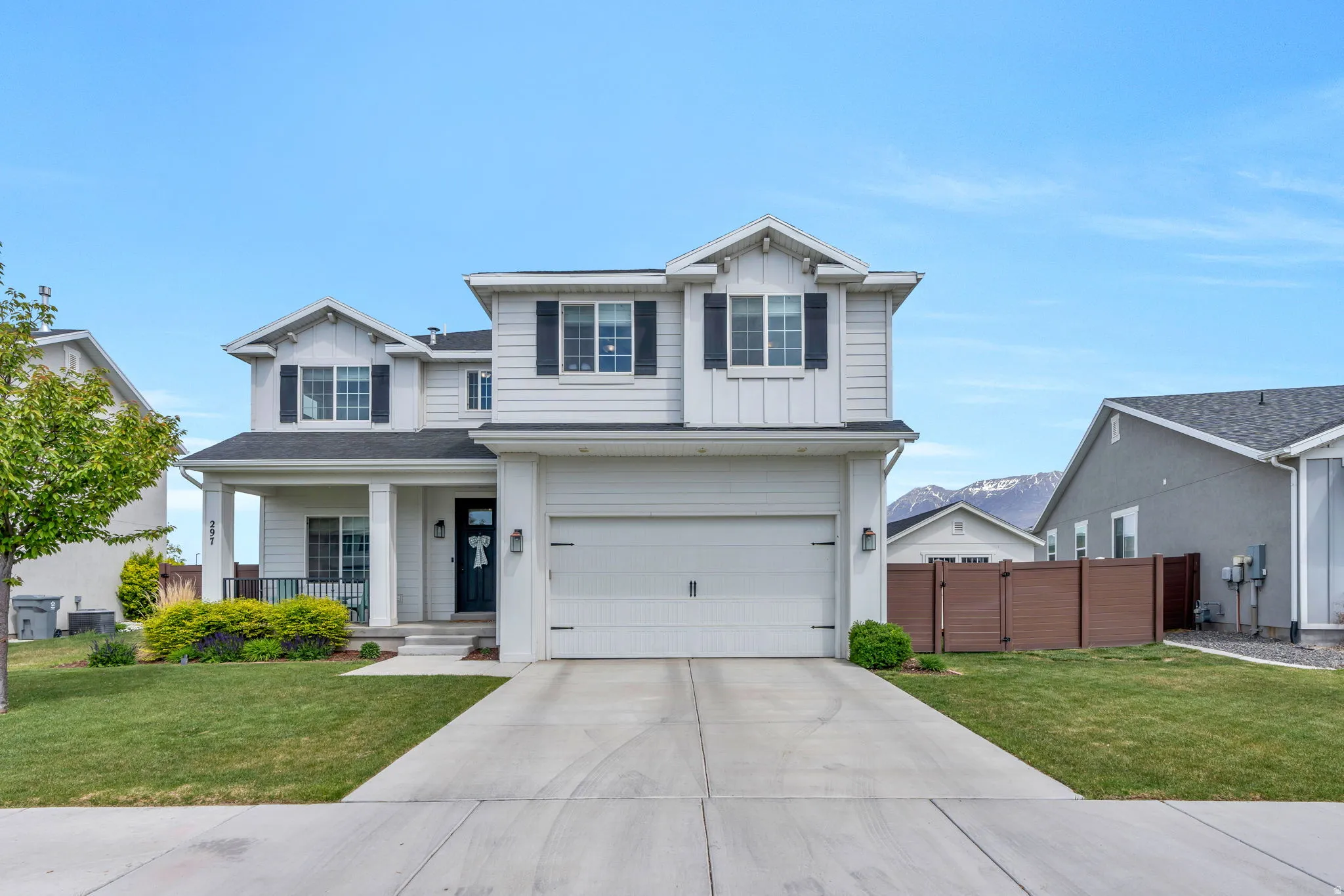 Traditional-style home with a gate, a porch, a garage, and driveway