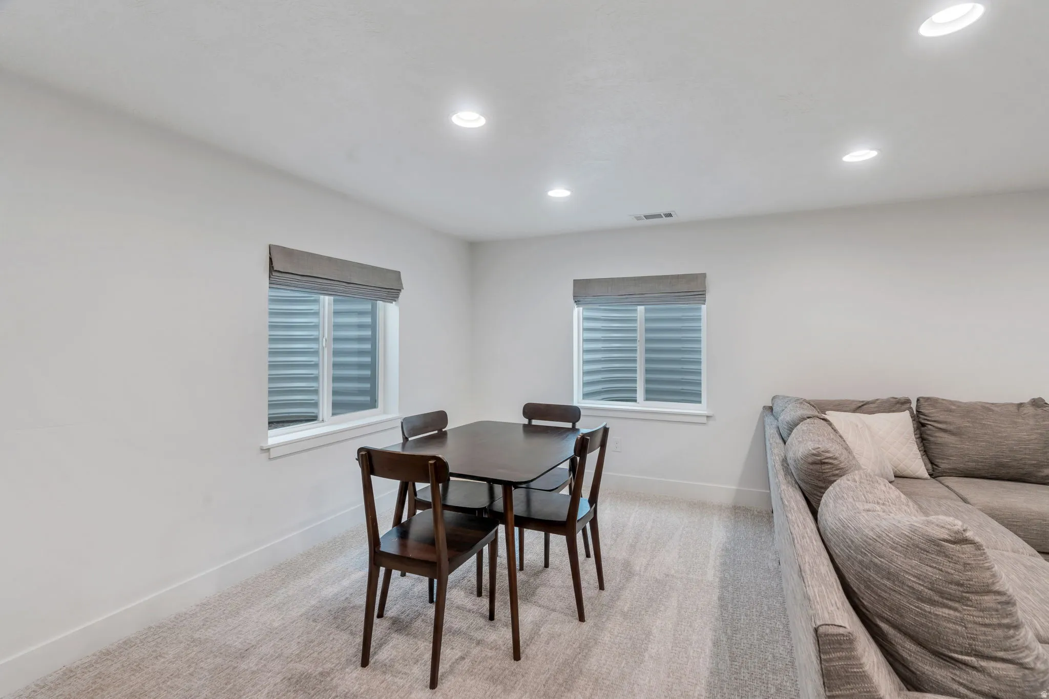 Dining area with light carpet and recessed lighting