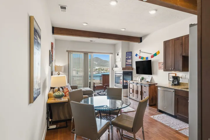 Dining space featuring a textured ceiling, a glass covered fireplace, beamed ceiling, dark wood-style floors, and recessed lighting