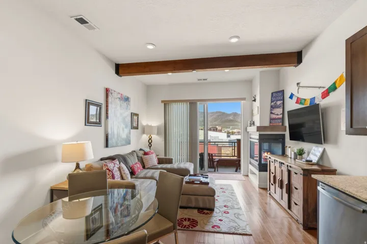 Living area featuring a glass covered fireplace, light wood-type flooring, beamed ceiling, recessed lighting, and a textured ceiling