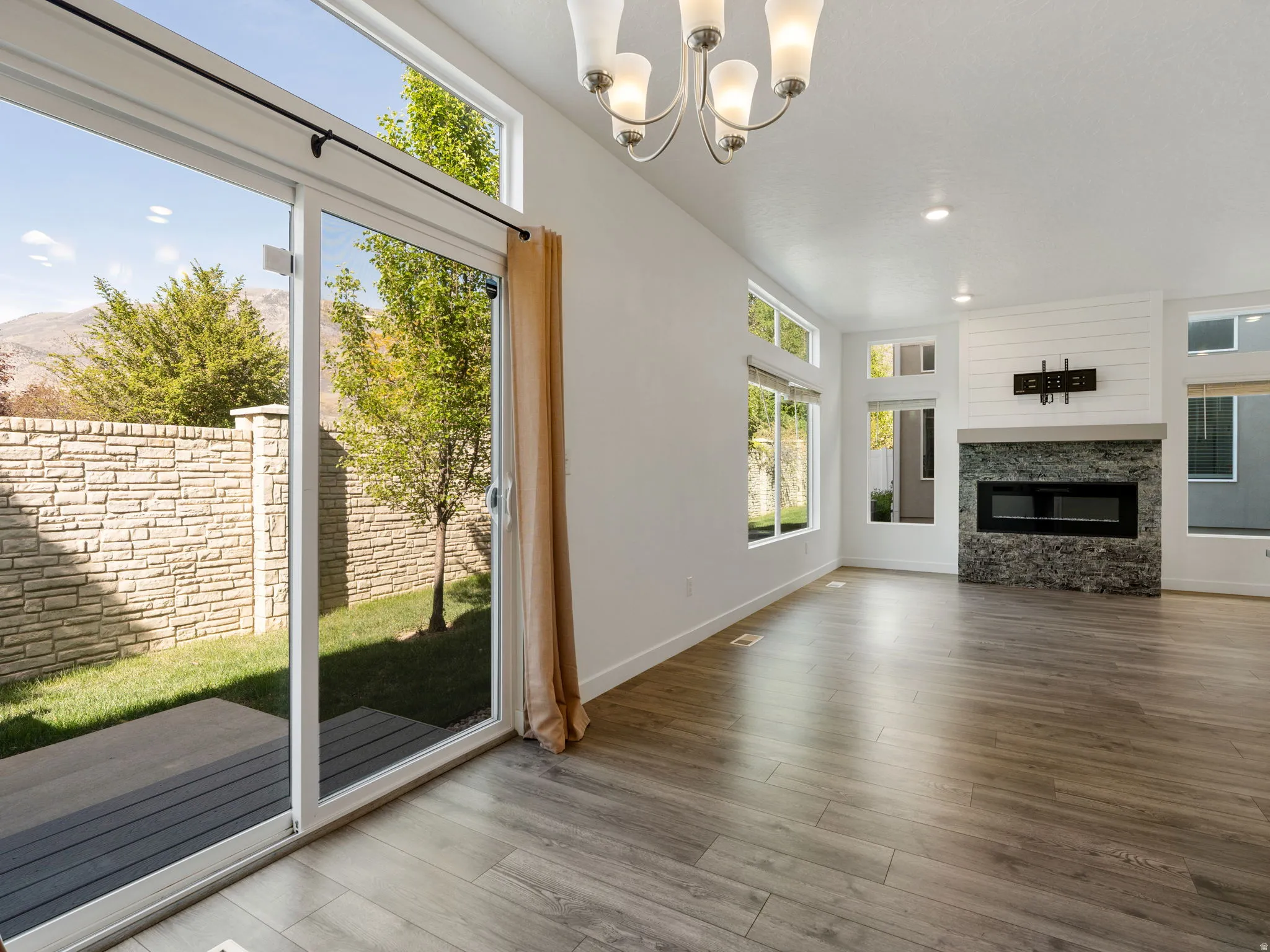 Unfurnished living room with a fireplace, suspended lighting, and wood finished floors