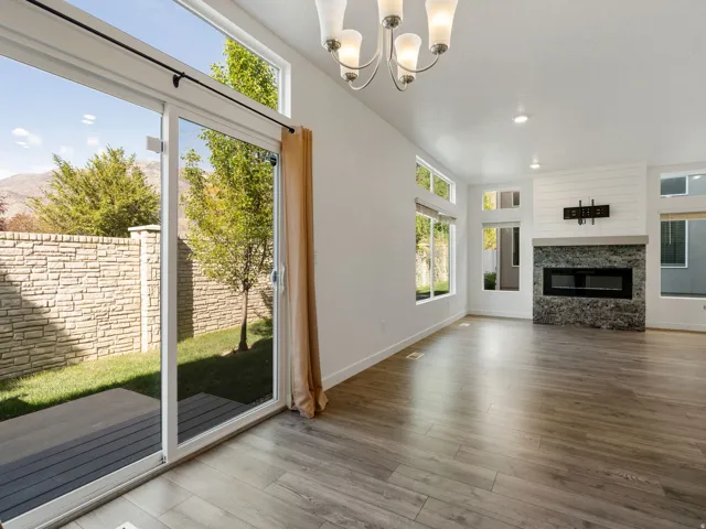 Unfurnished living room with a fireplace, suspended lighting, and wood finished floors