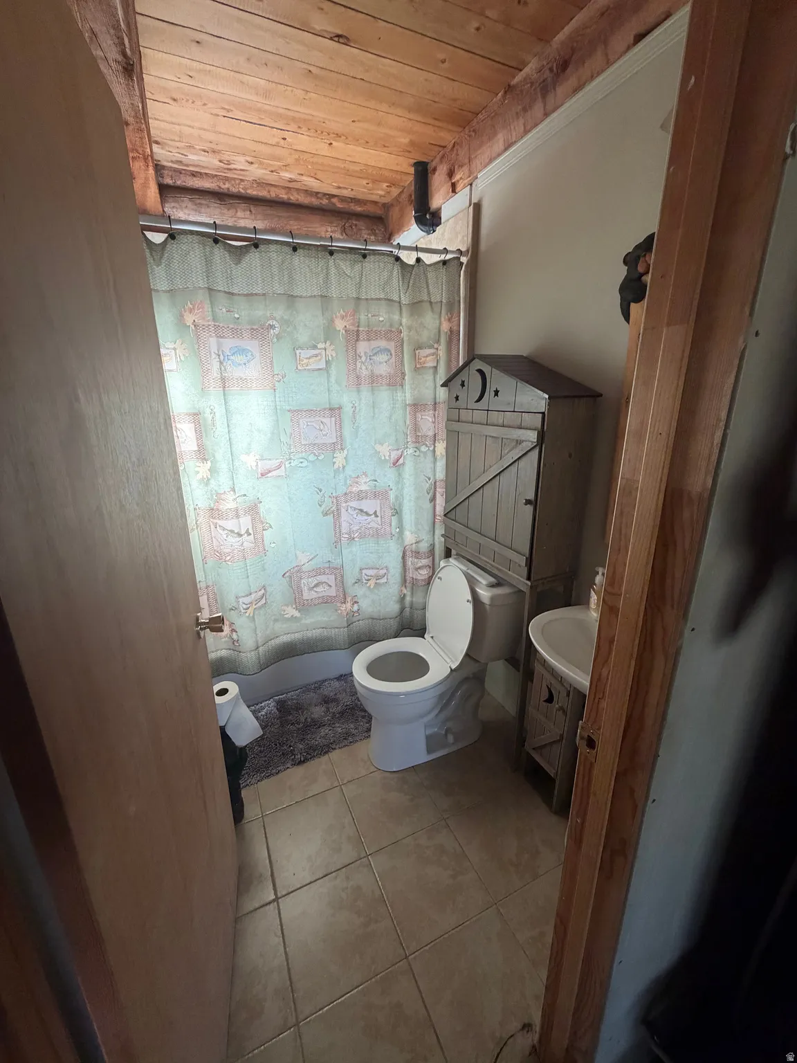 Bathroom with wooden ceiling, light tile patterned floors, and a shower with shower curtain