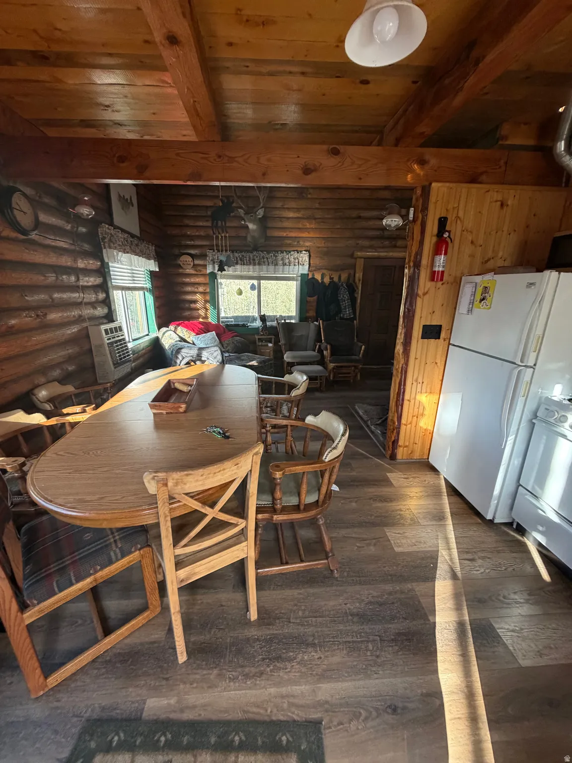 Dining area with a wooden ceiling with exposed beams, dark wood-style flooring, heating unit, and rustic walls