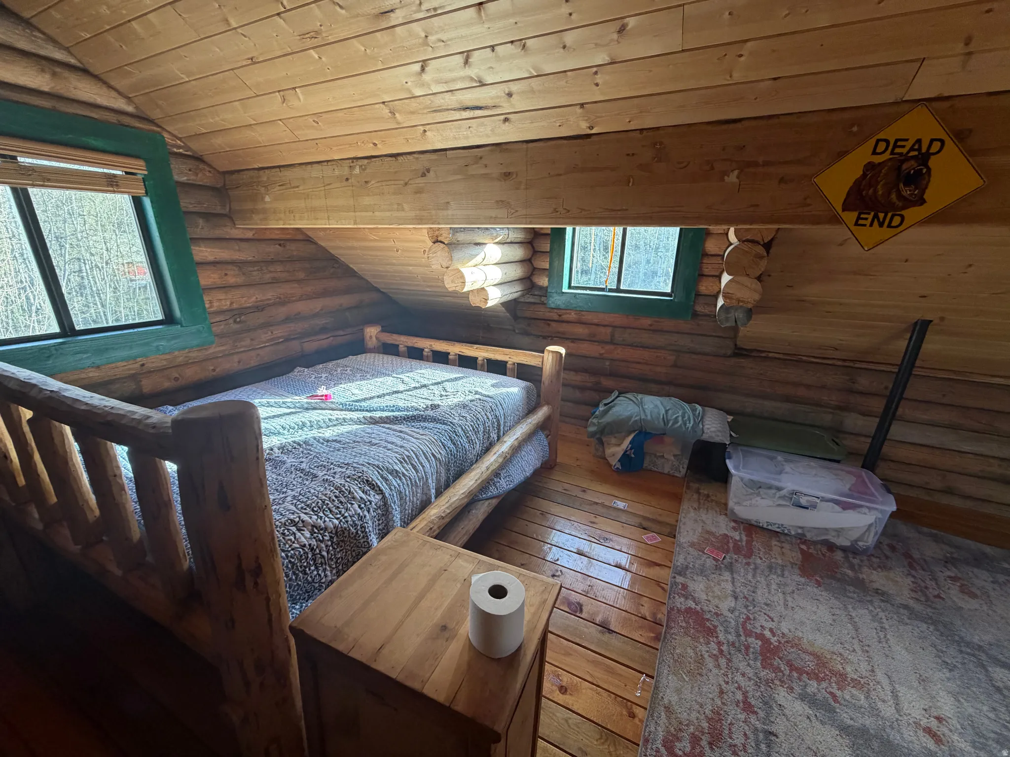 Bedroom featuring log walls, a vaulted wood ceiling, and hardwood / wood-style flooring