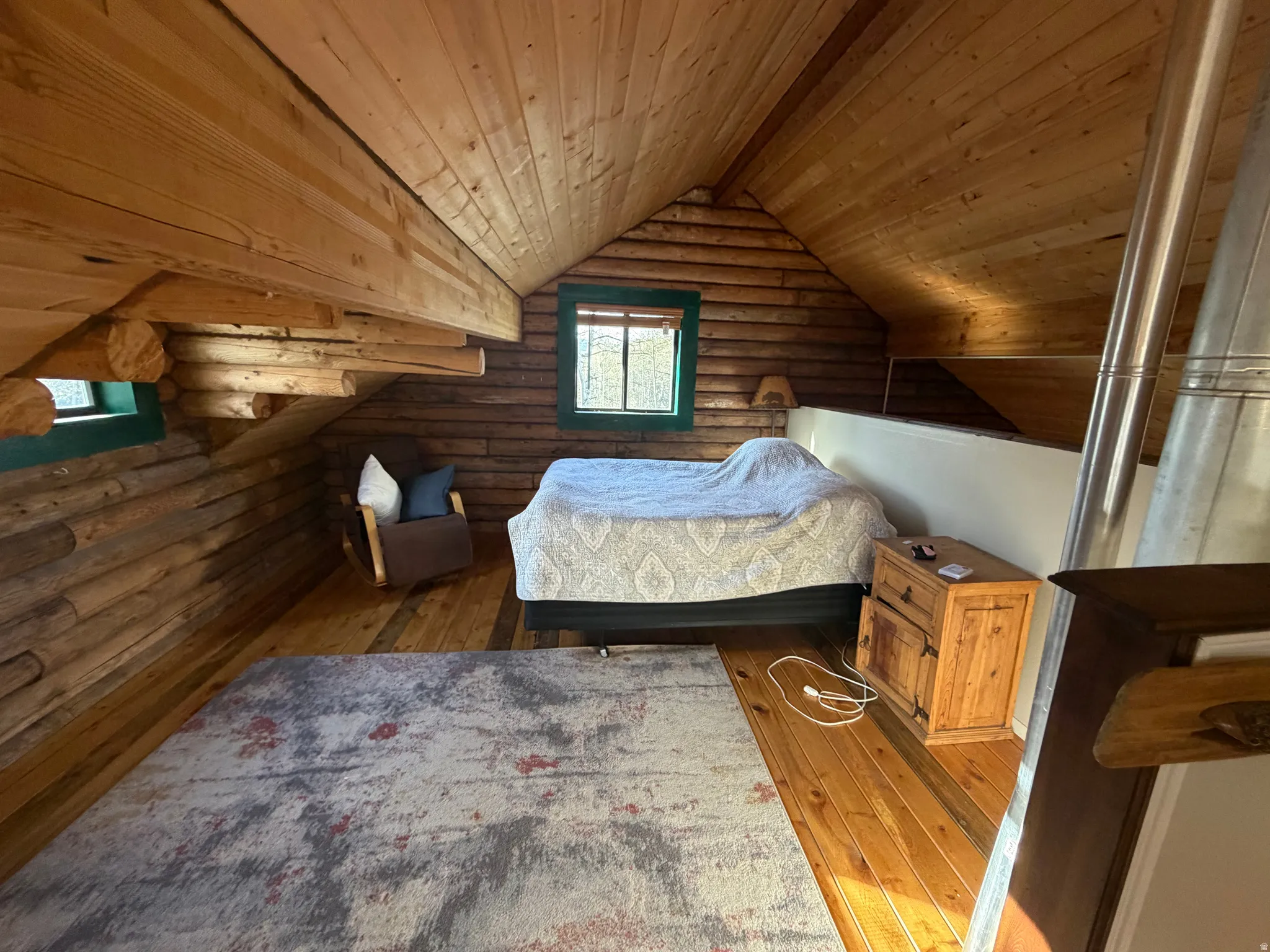 Bedroom with rustic walls, a vaulted wood ceiling, and wood-type flooring