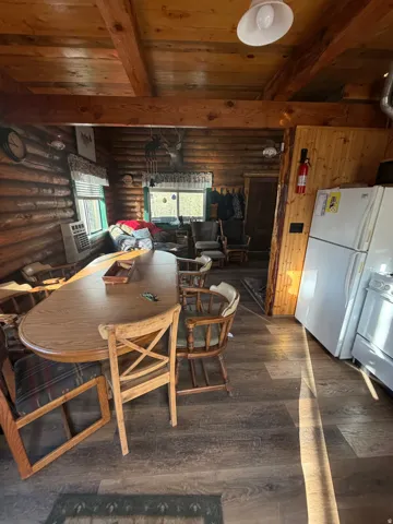 Dining area with a wooden ceiling with exposed beams, dark wood-style flooring, heating unit, and rustic walls