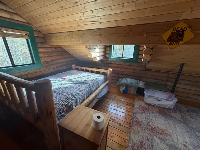 Bedroom featuring log walls, a vaulted wood ceiling, and hardwood / wood-style flooring