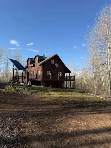 Rear view of house with ground mounted solar panels and a deck