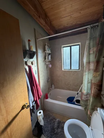 Bathroom featuring shower / tub combo with curtain, wood ceiling, and tile patterned floors