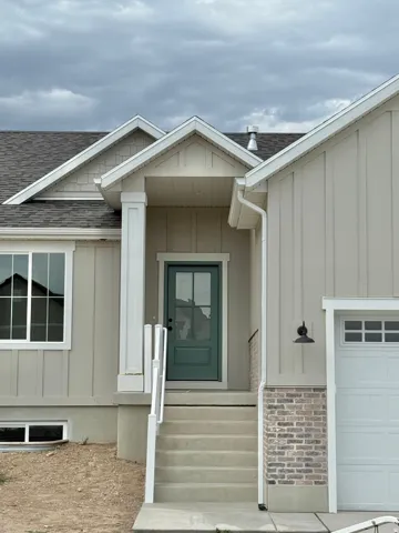 Inviting entryway featuring a covered porch with a stately column, a deep green front door with windowpanes, and concrete steps with white railings