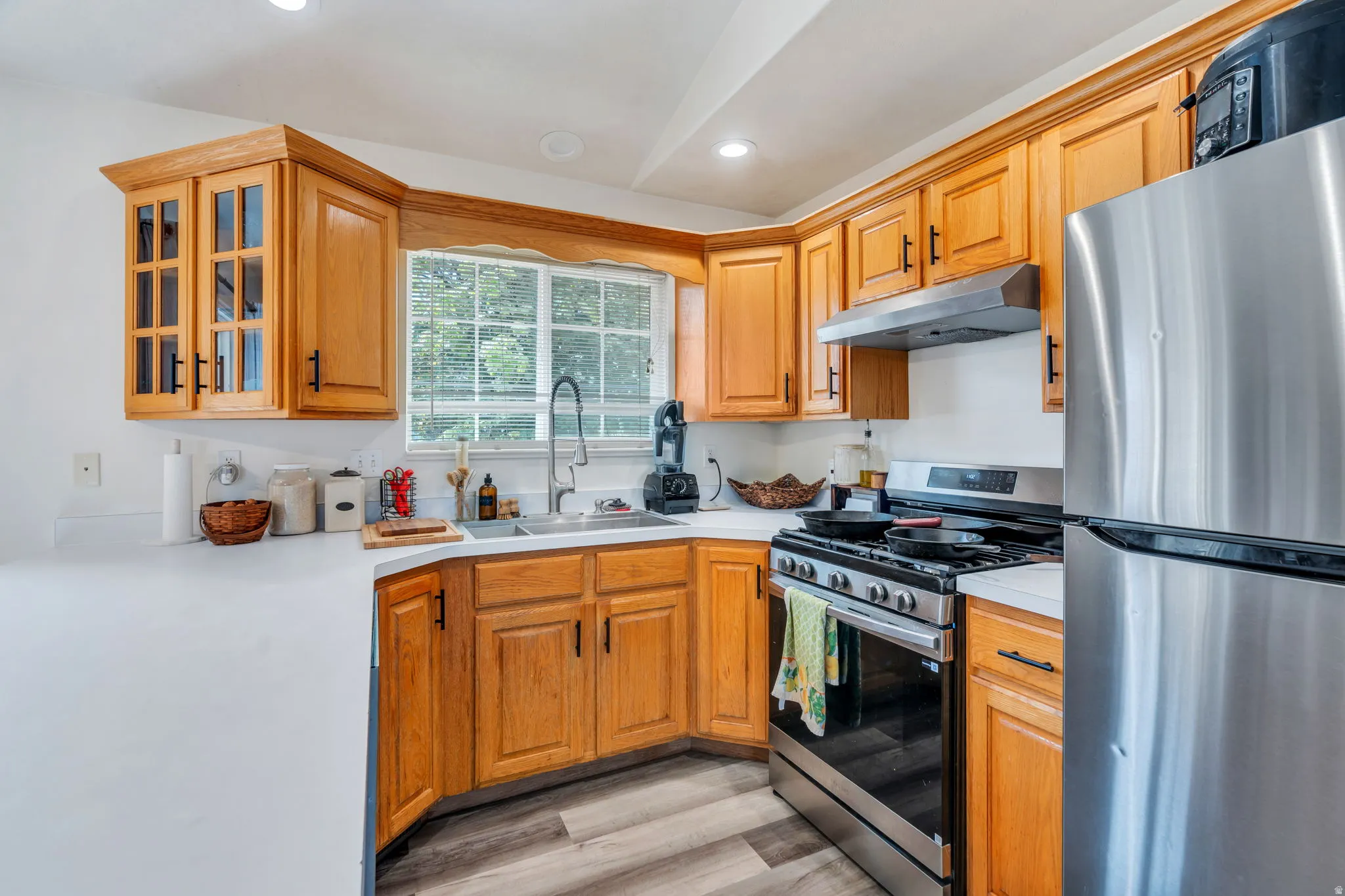 Kitchen featuring stainless steel appliances, light countertops, light wood-style floors, recessed lighting, and wood finish cabinets
