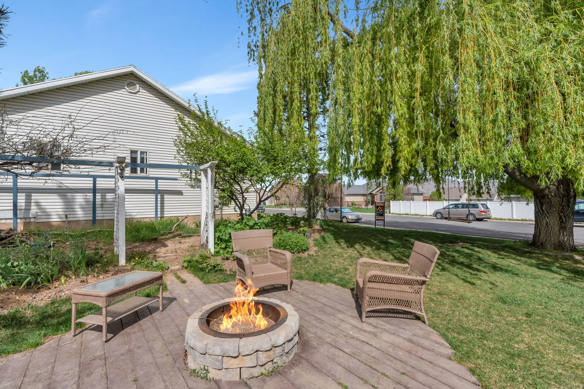 Side yard with a shaded Willow Tree and an outdoor fire pit