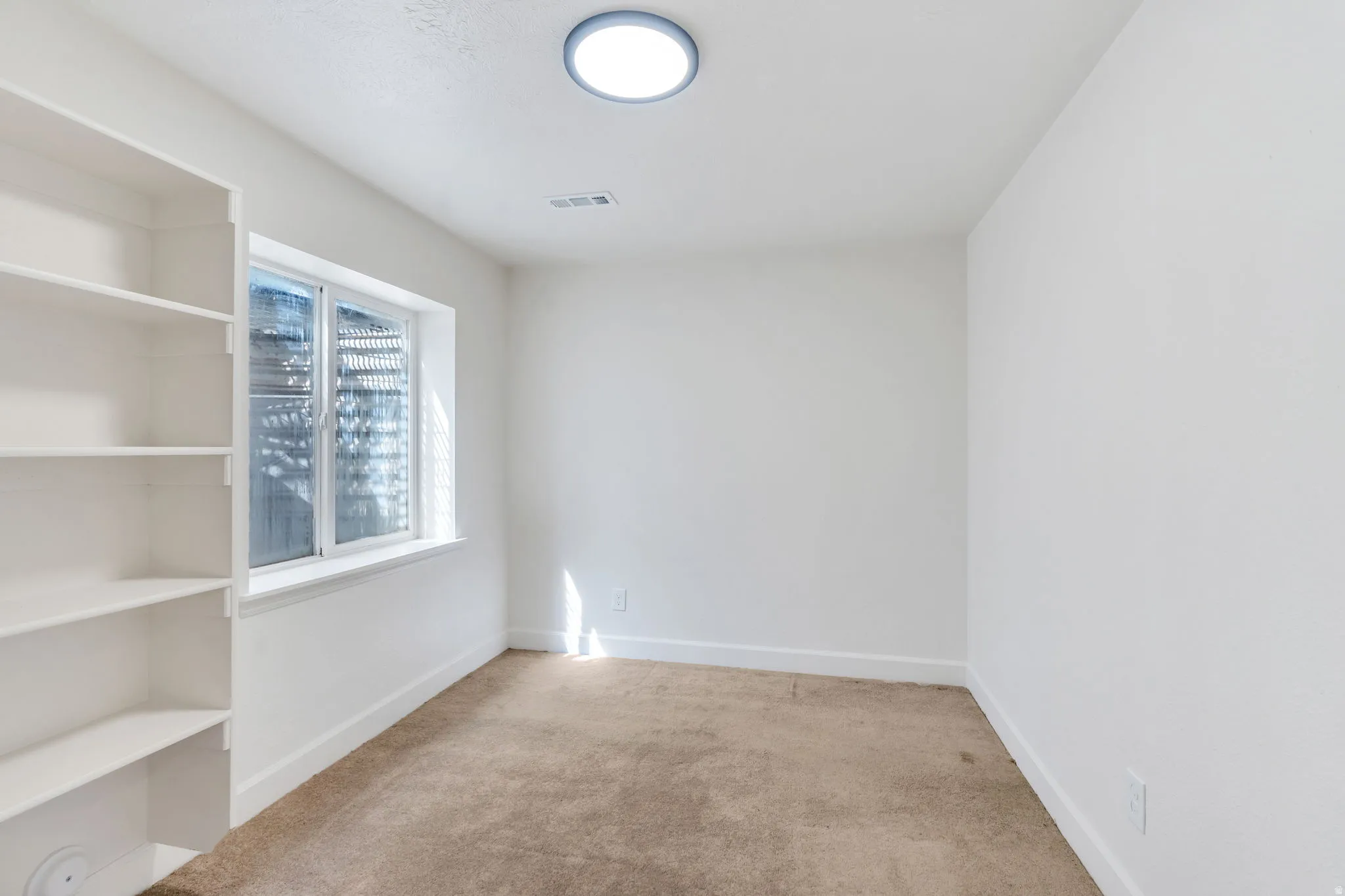 Spare room with baseboards and light colored carpet