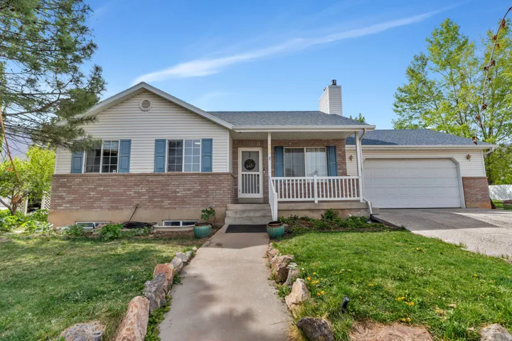 Ranch-style house with covered porch, brick siding, an attached garage, and a front yard