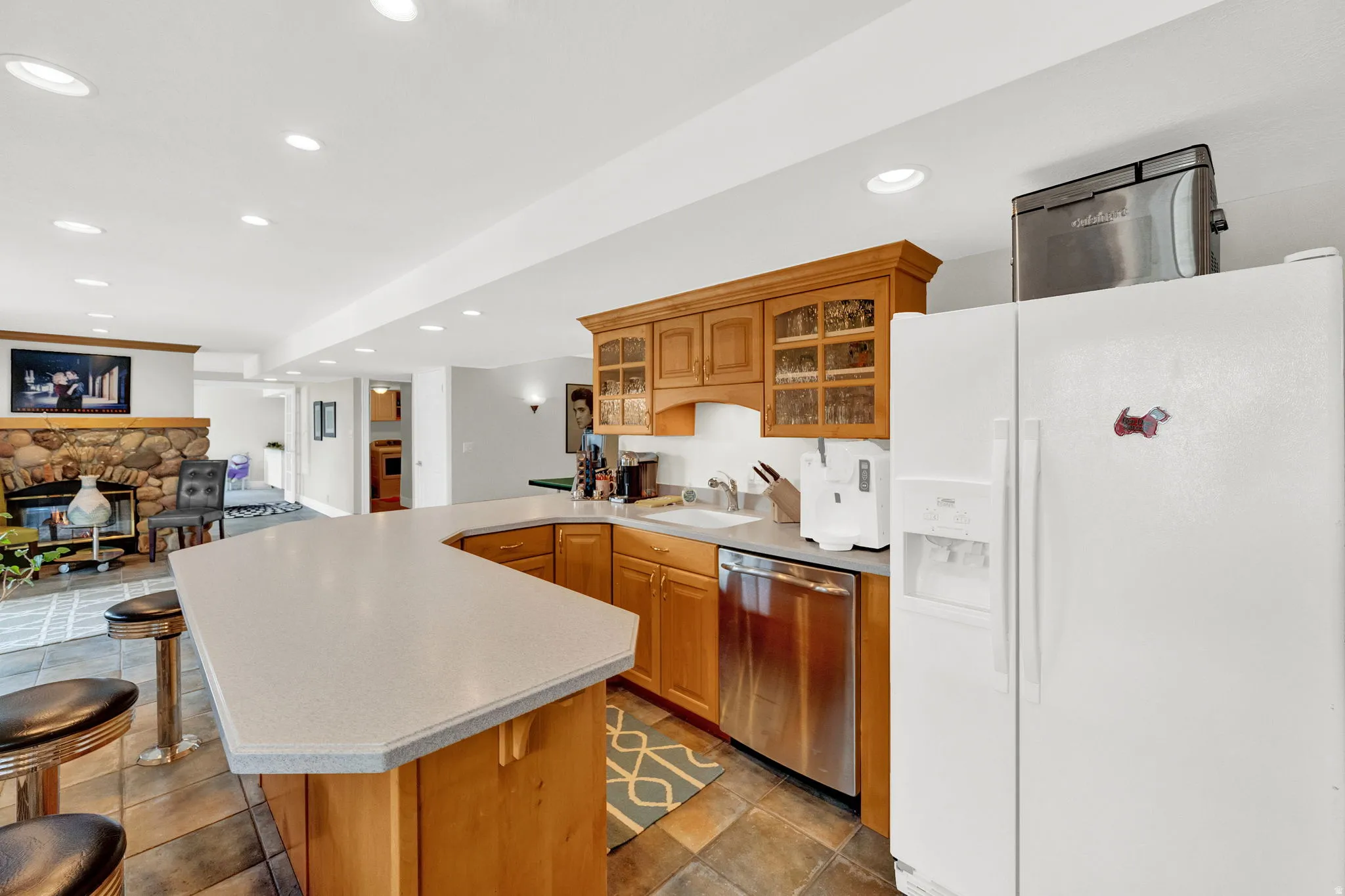 Kitchen with white fridge with ice dispenser, glass insert cabinets, recessed lighting, light countertops, and dishwasher