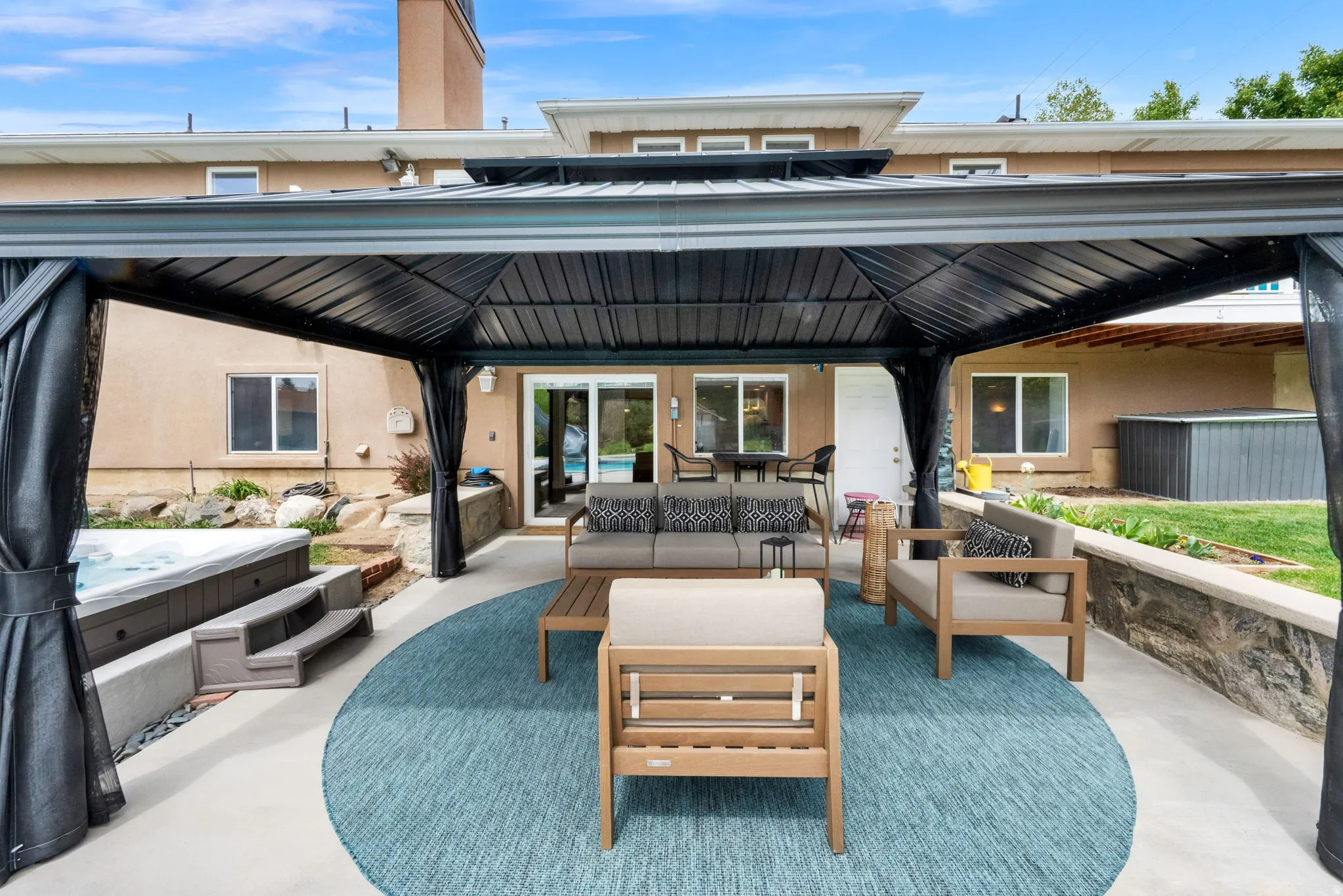 View of patio featuring a hot tub, an outdoor hangout area, and a gazebo