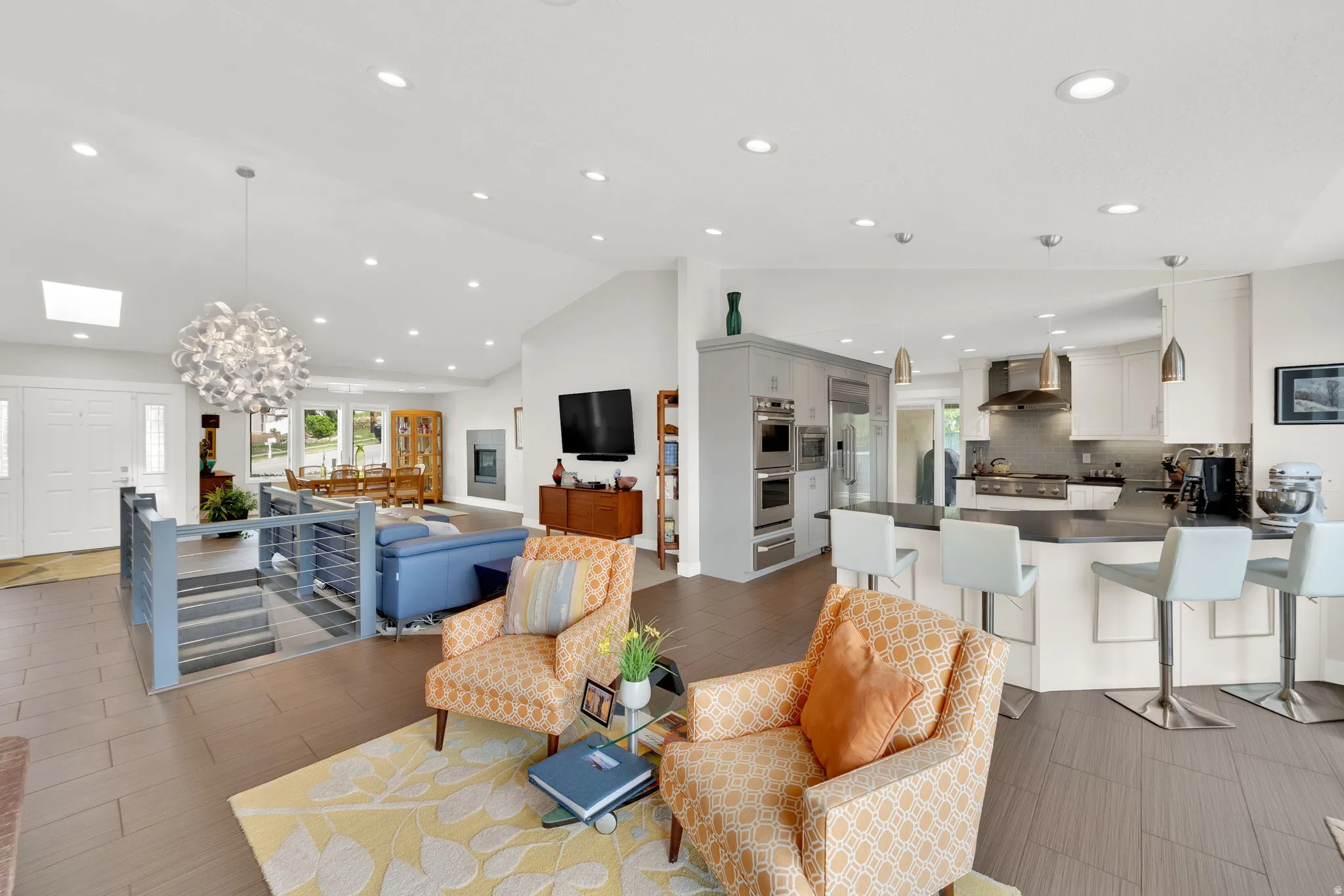 Living room with vaulted ceiling, hanging lights, and tile floors