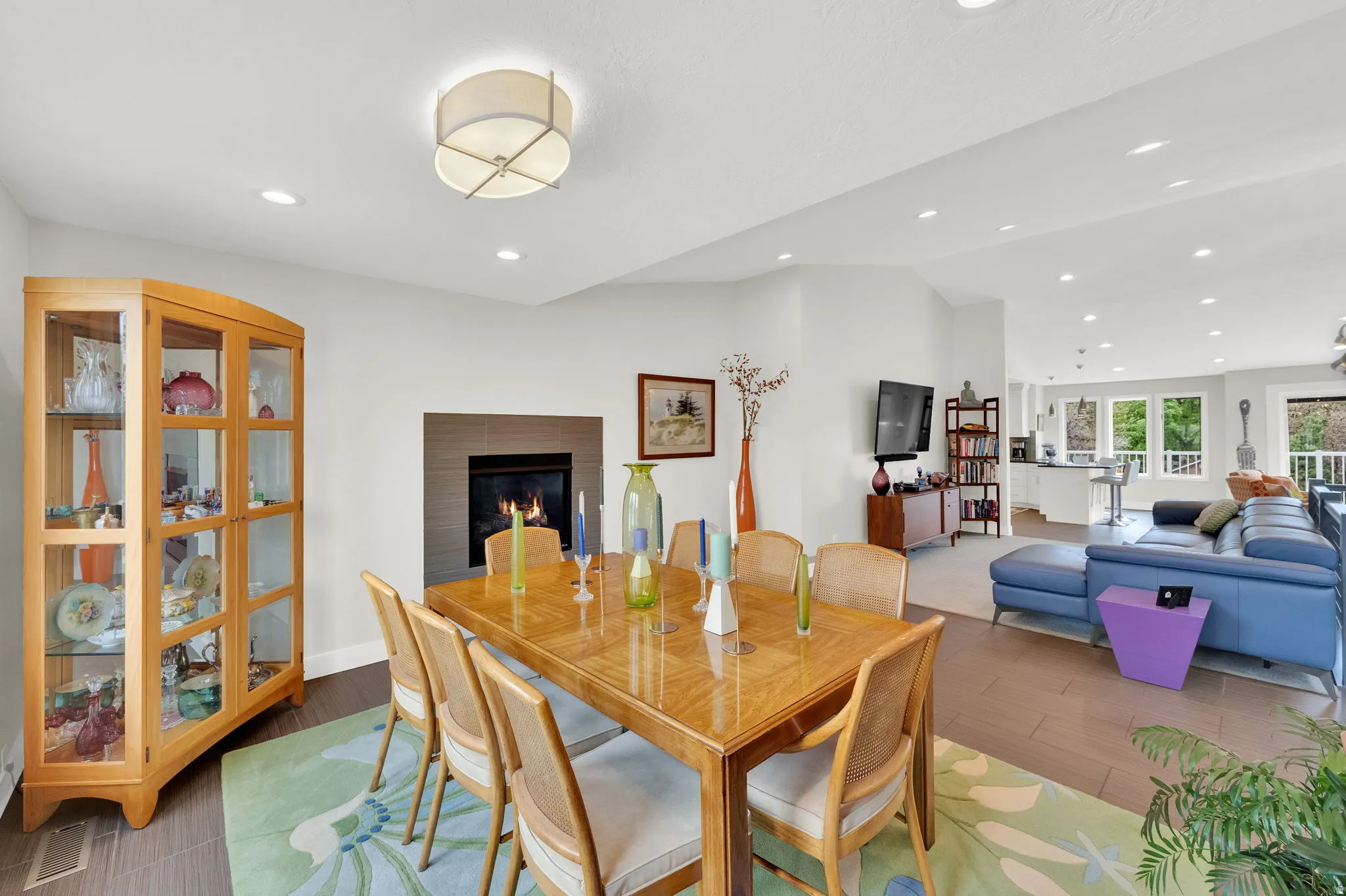 Dining area featuring a glass covered fireplace, light wood finished floors, recessed lighting, and lofted ceiling