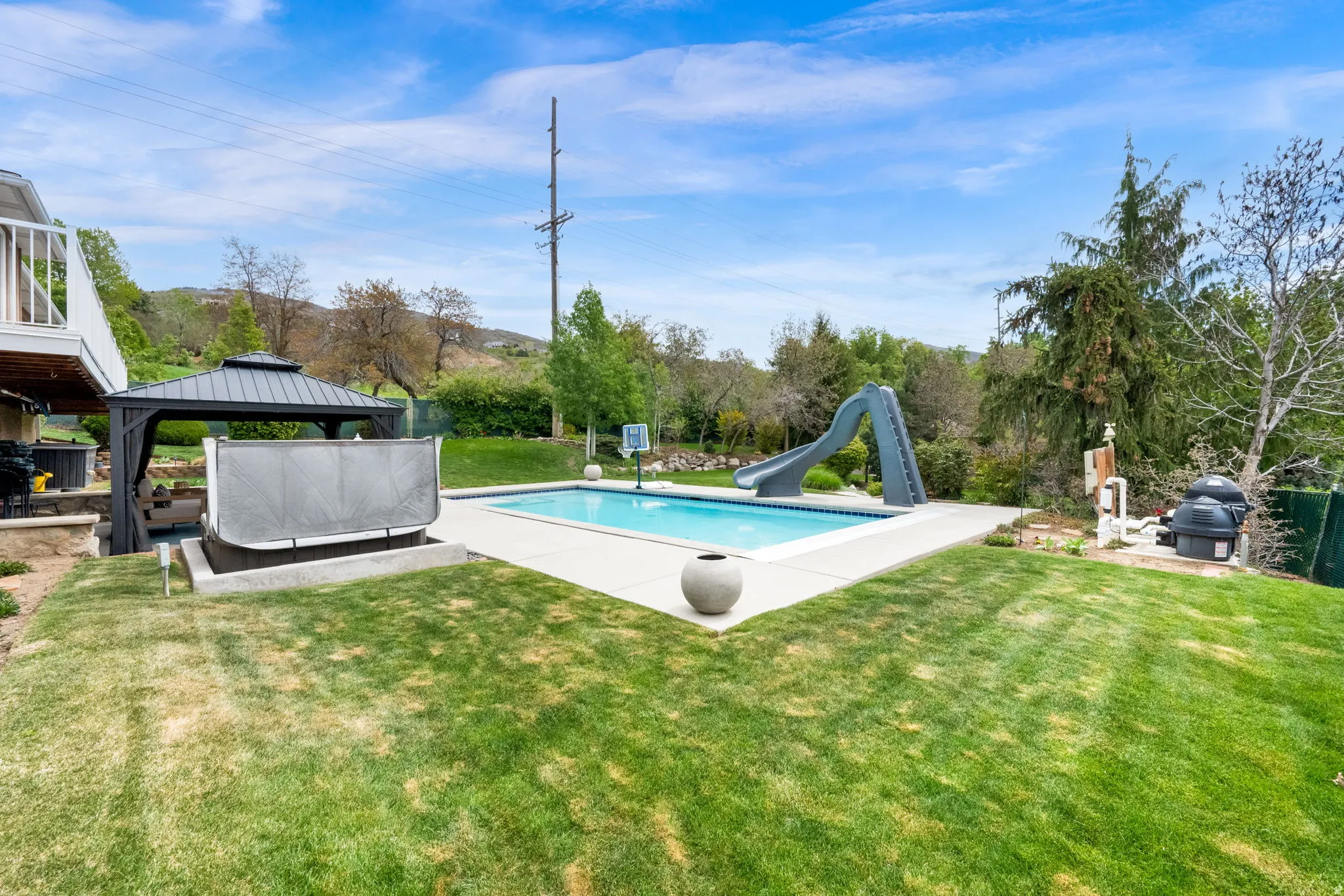 Swimming pool featuring a water slide, a patio area, a gazebo, and a lawn
