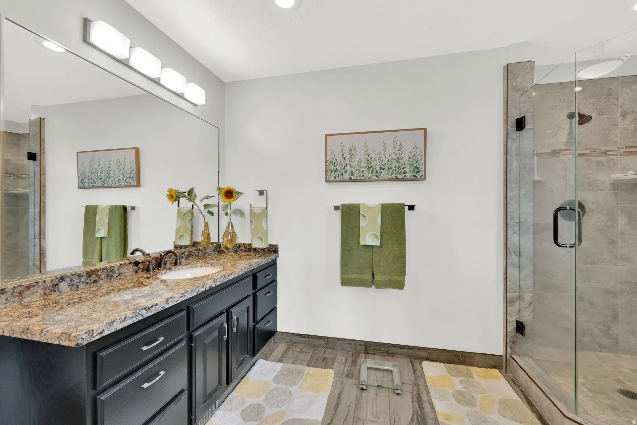 Bathroom with a stall shower, vanity, light tile floors, and recessed lighting