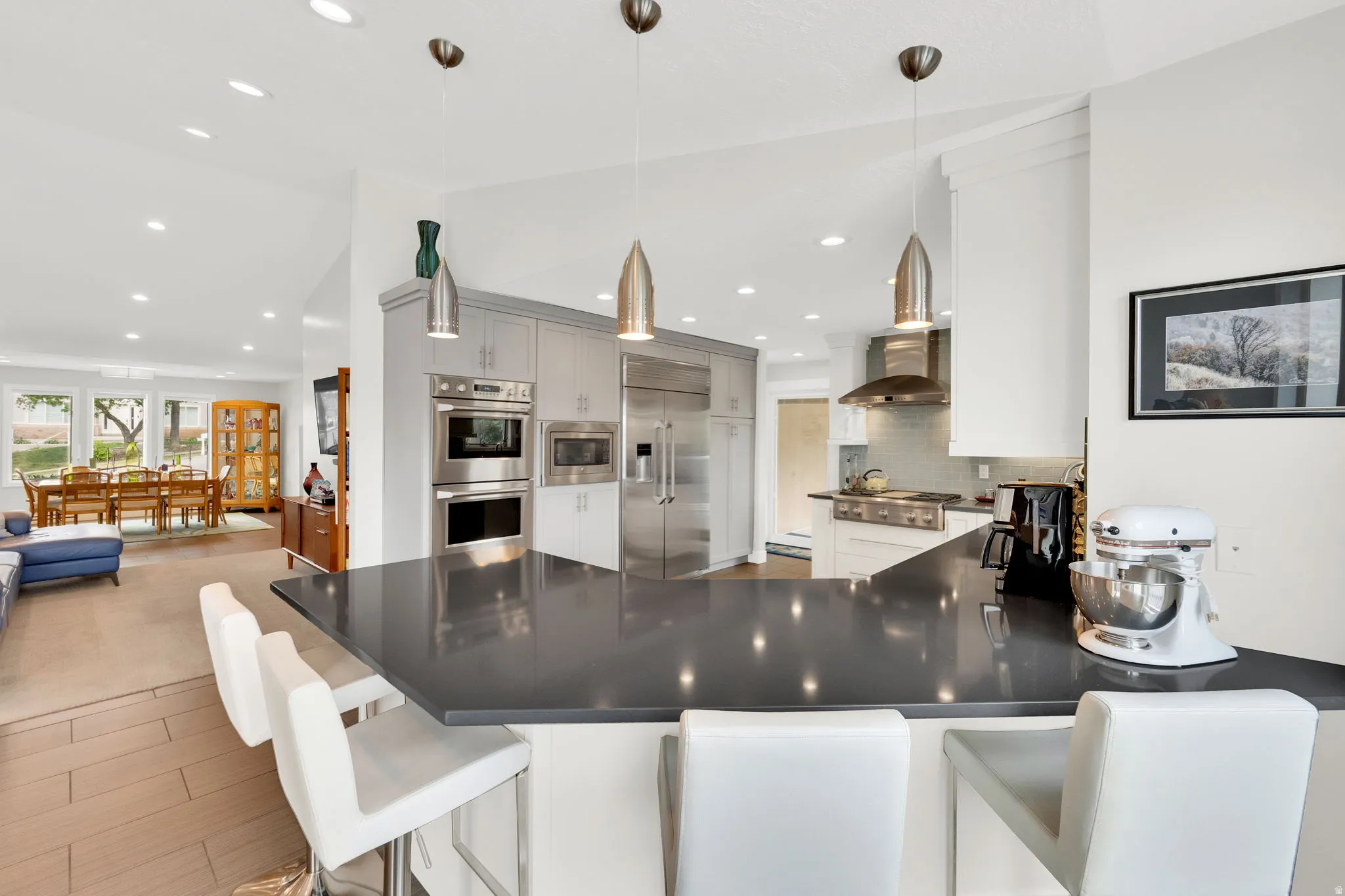 Kitchen featuring a breakfast bar area, a peninsula, built in appliances, tasteful backsplash, and open floor plan