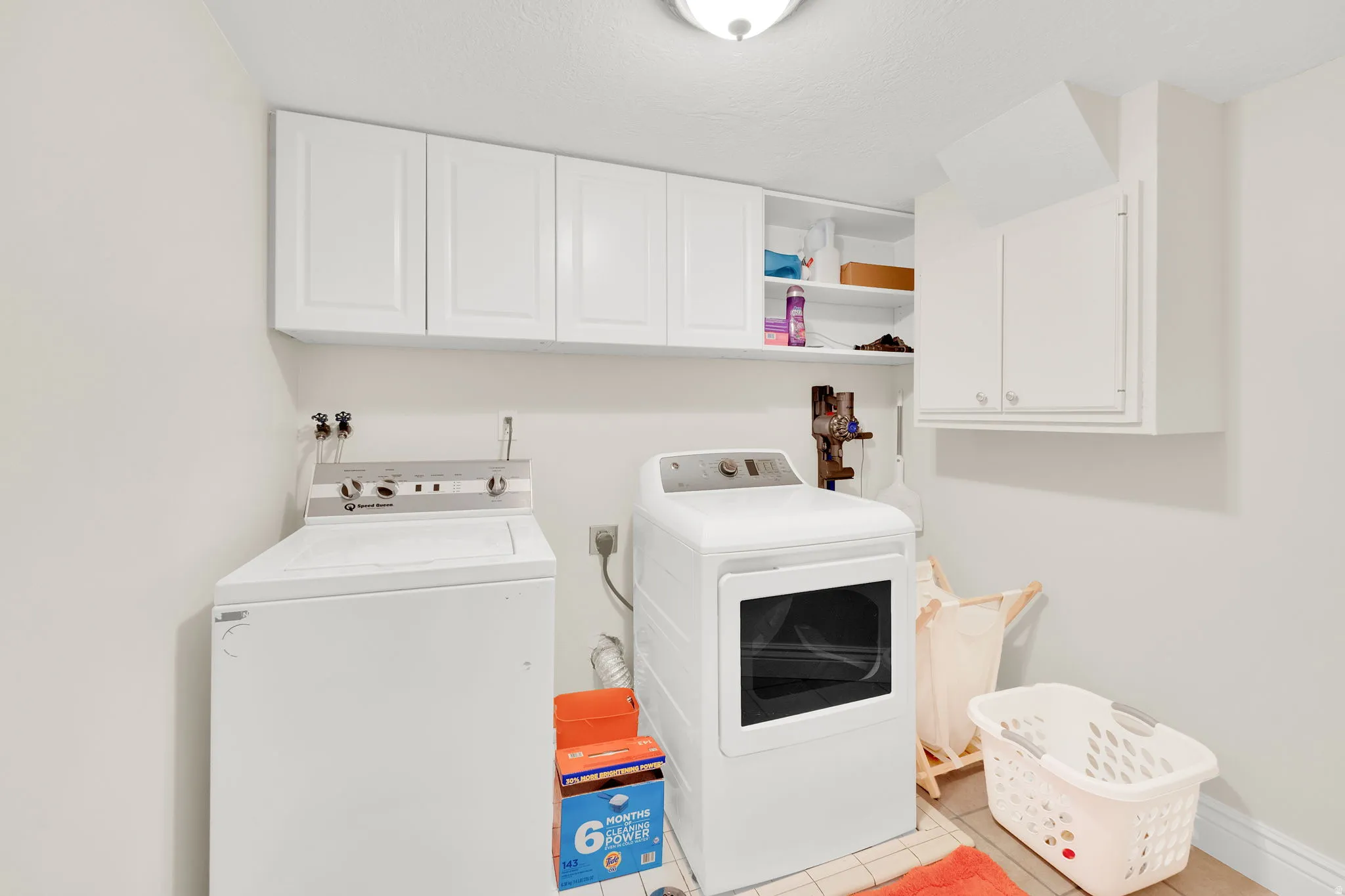 Laundry room featuring cabinet space, washing machine and dryer, and light tile patterned floors