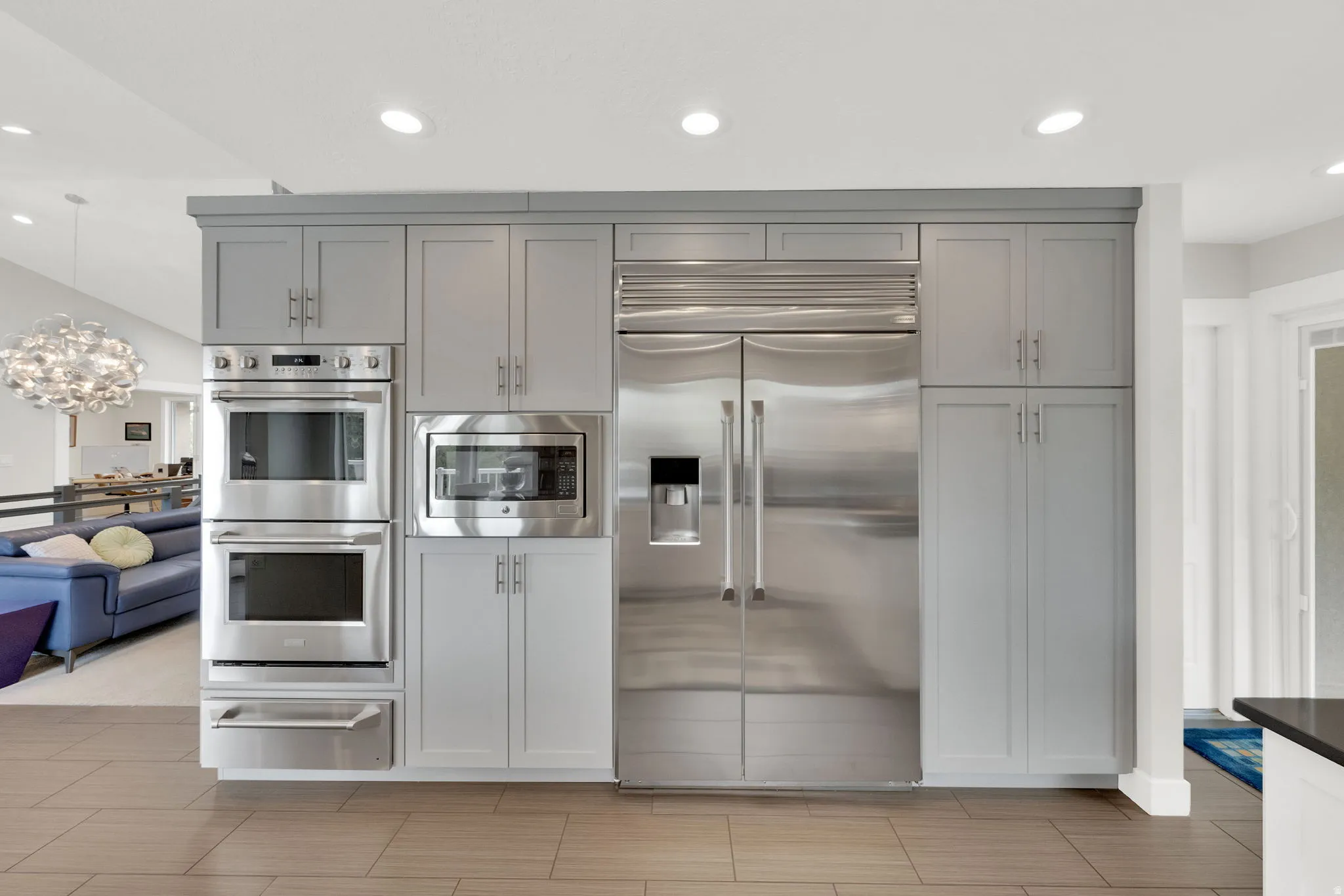Kitchen with built in appliances, a warming drawer, a chandelier, gray cabinets, and open floor plan