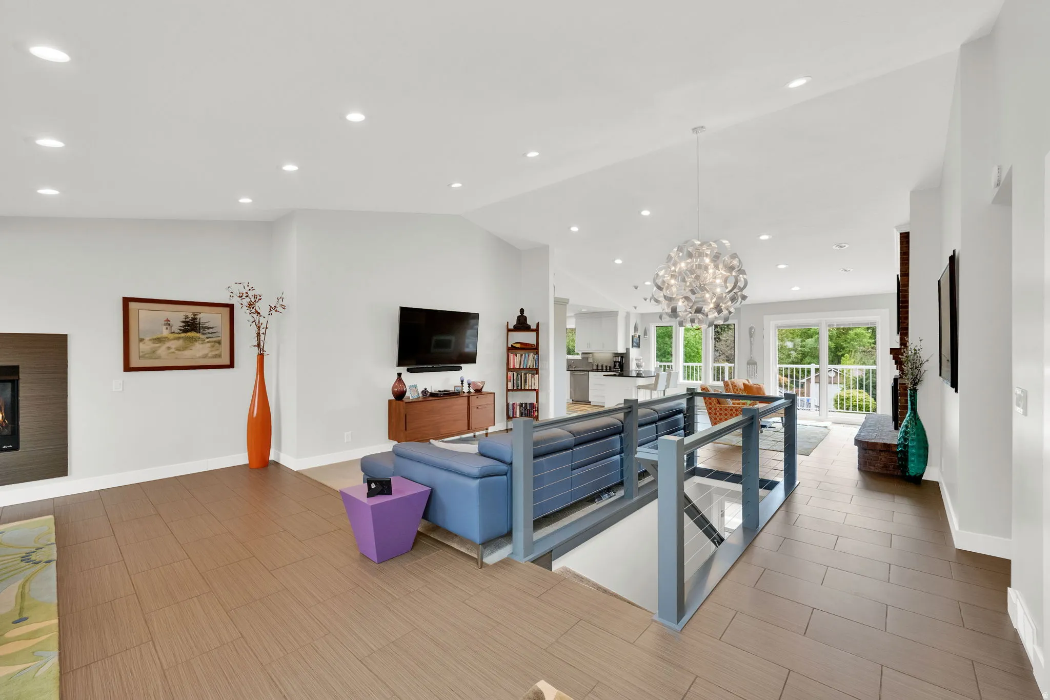 Living room with a glass covered fireplace, suspended lighting, vaulted ceiling, and french doors