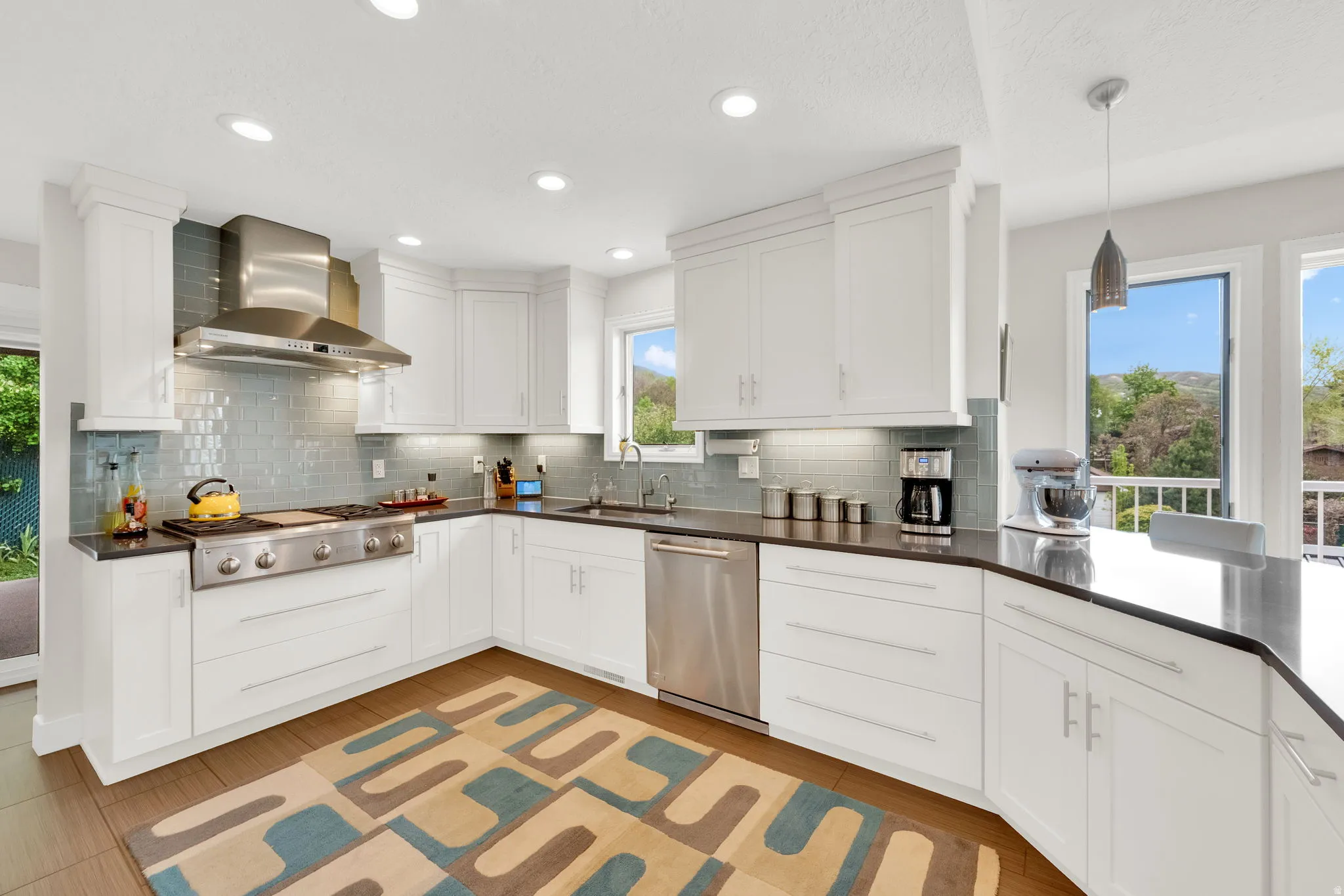 Kitchen with white cabinetry, stainless steel appliances, hanging light fixtures, and decorative backsplash
