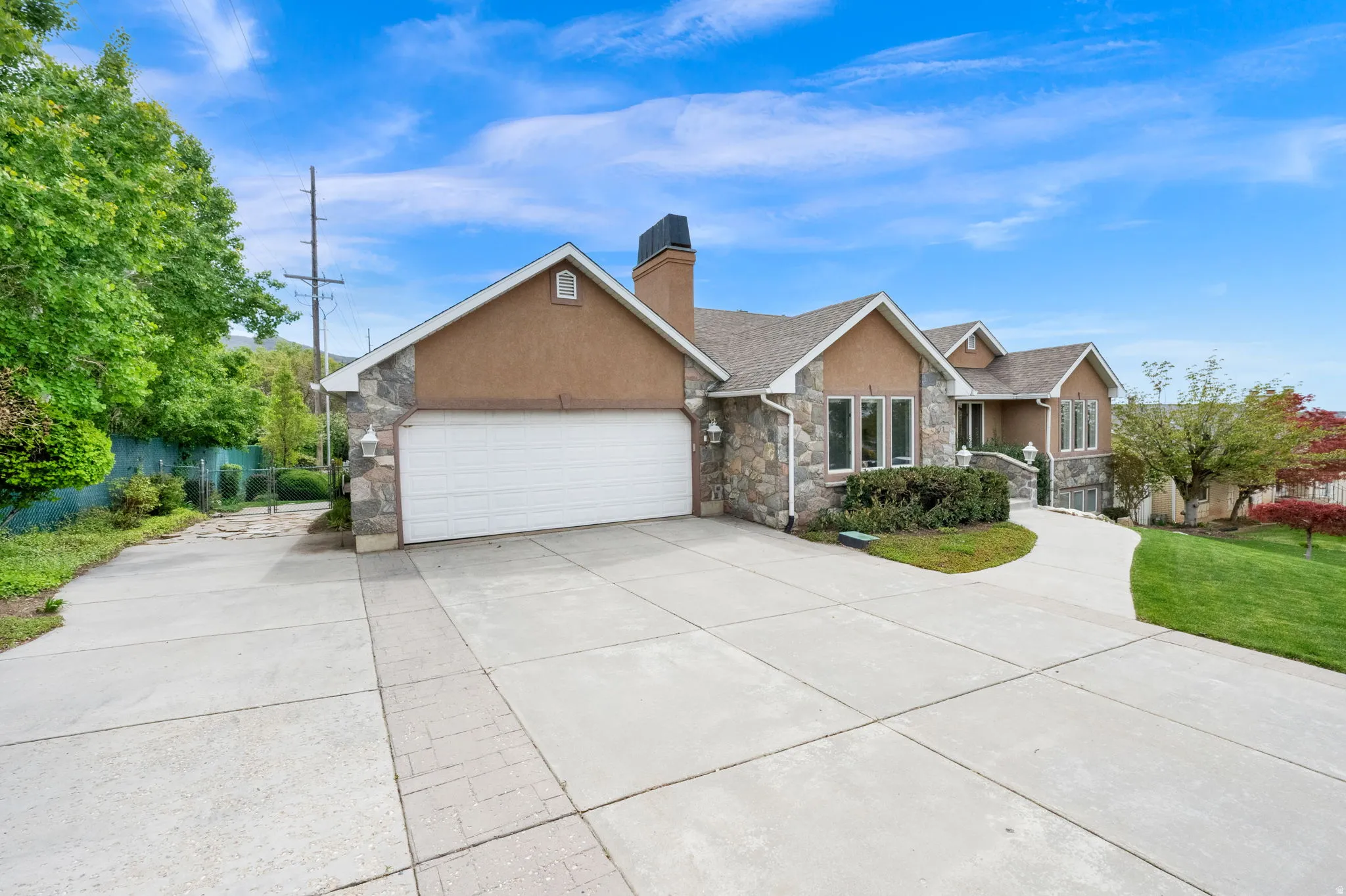 View of front of property featuring stone siding, concrete driveway, a garage, stucco siding, and a chimney