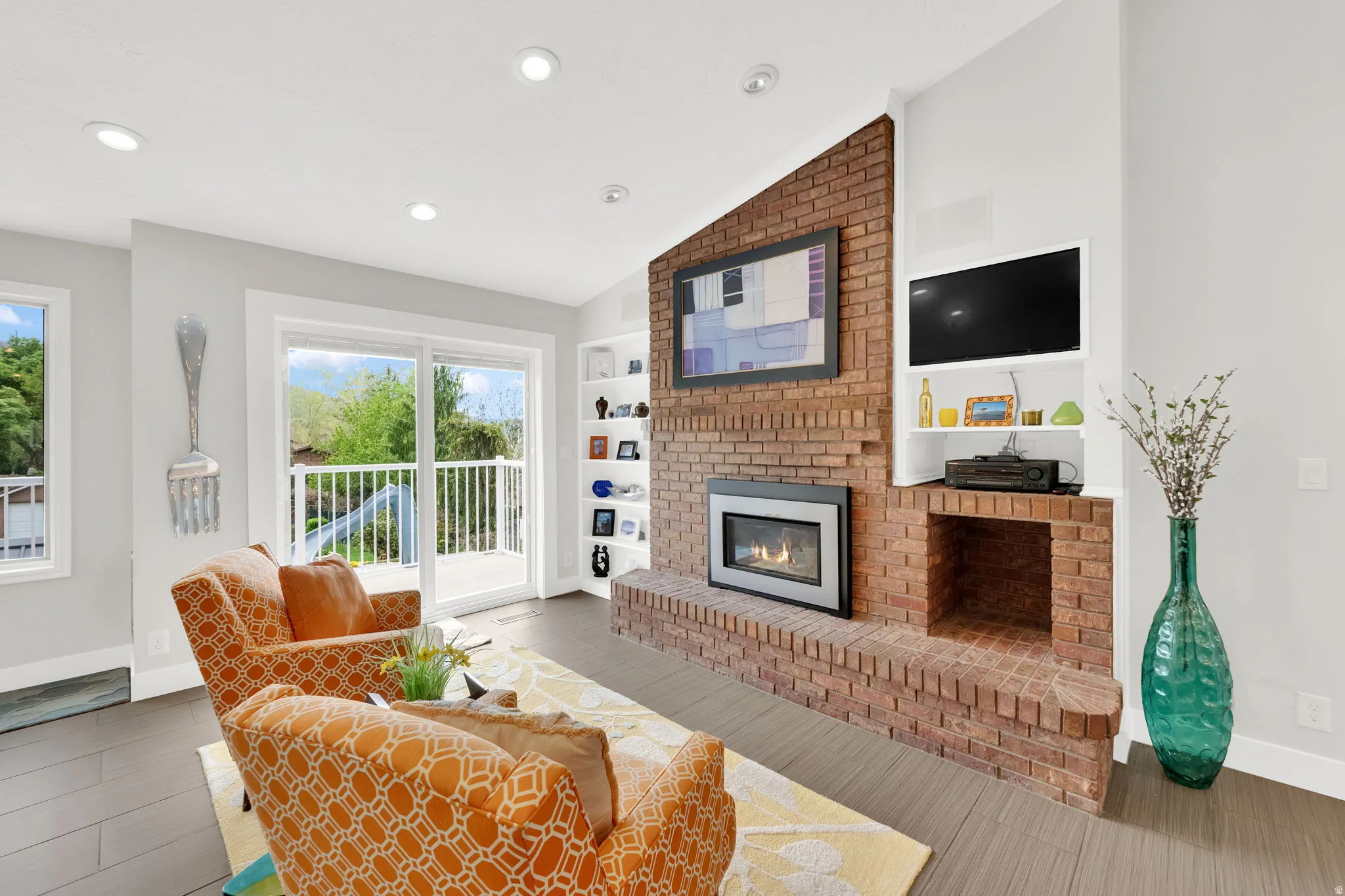 Living room featuring lofted ceiling, a brick fireplace, light wood-style flooring, recessed lighting, and built in features