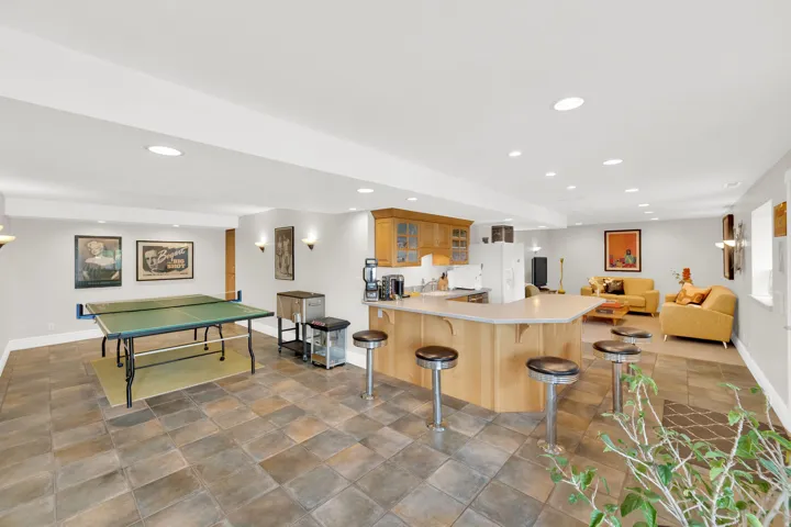 Kitchen featuring a kitchen bar, open floor plan, glass fronted cabinets, a peninsula, and recessed lighting