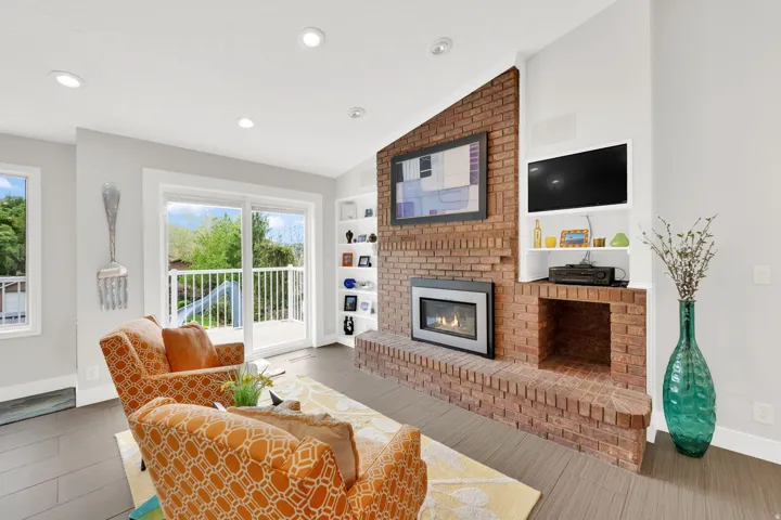Living room featuring lofted ceiling, a brick fireplace, light wood-style flooring, recessed lighting, and built in features